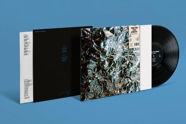 Schallplatte mit Folienhülle und schwarzem Sleeve auf blauem Hintergrund.