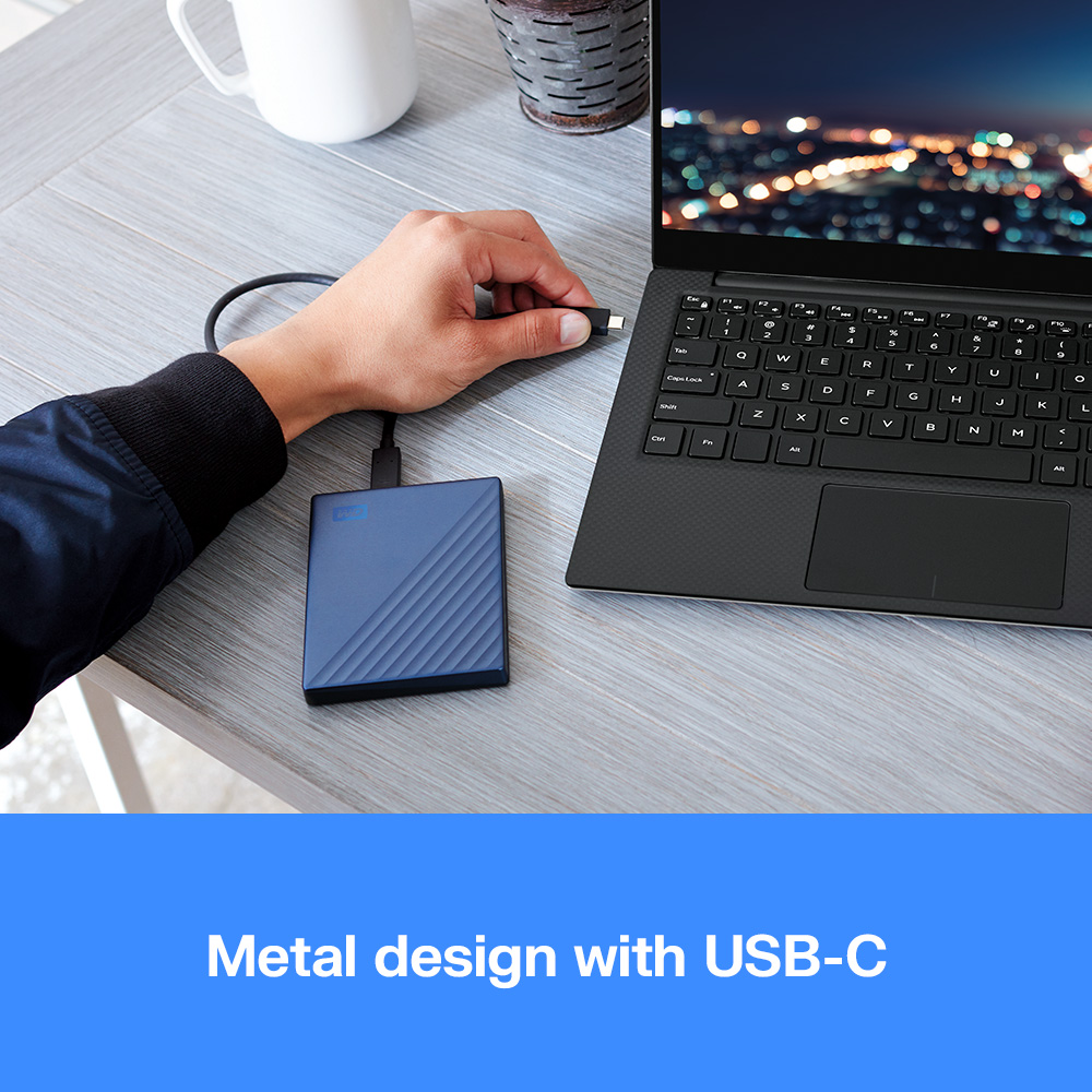 Un uomo collega un hard disk esterno blu con USB-C a un laptop.
