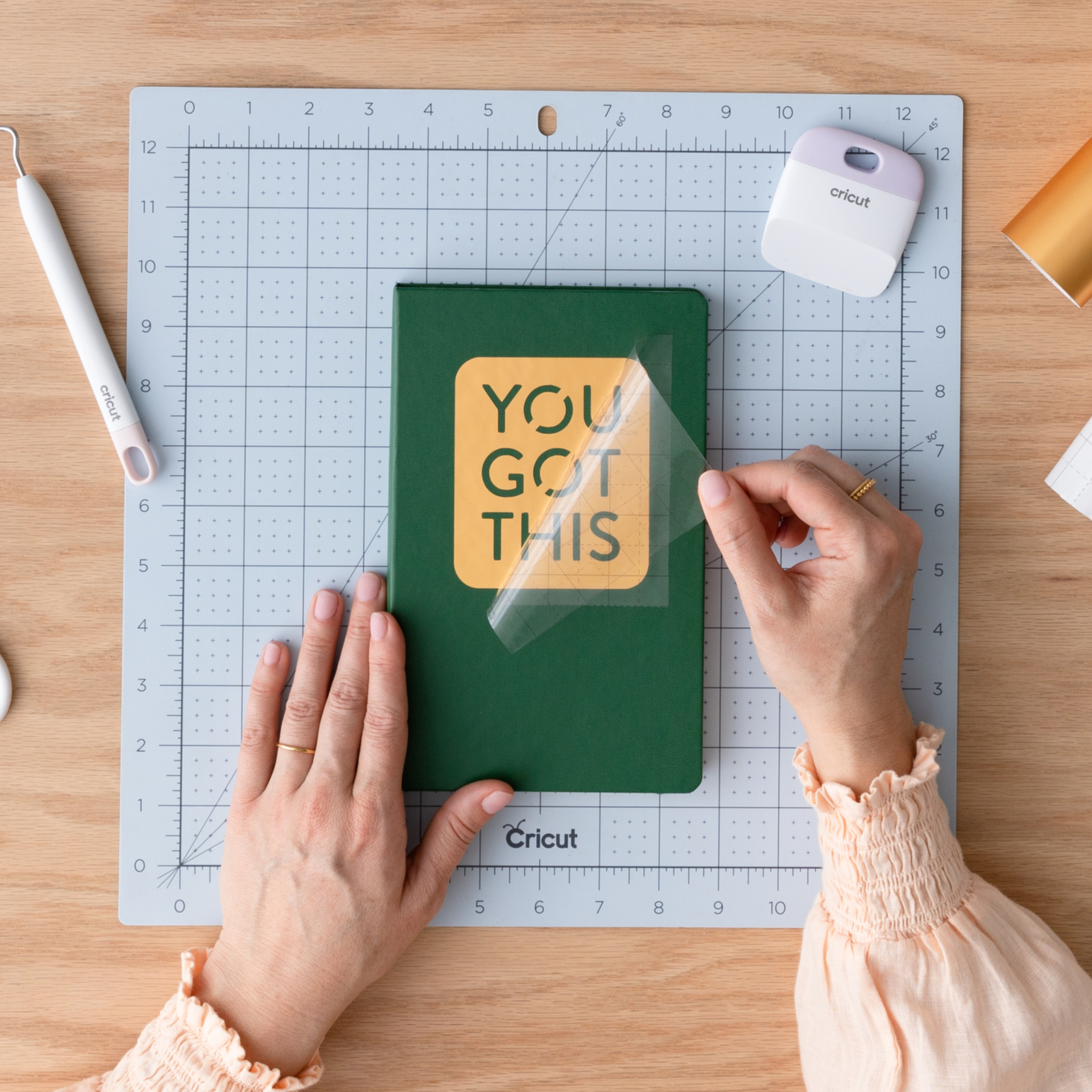 Bir el, üzerinde "YOU GOT THIS" yazan yeşil bir defterden transfer bandını soyuyor.