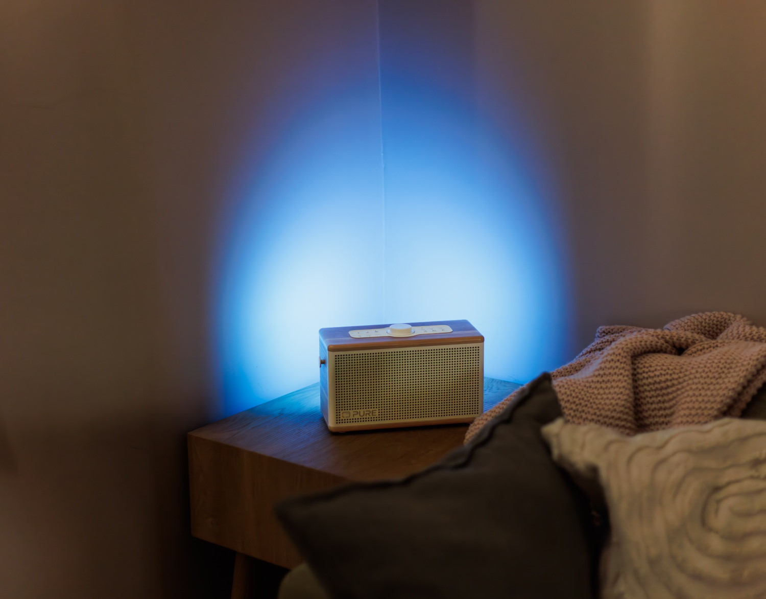 Ein Holzradio mit Metallgitter steht auf einem Nachttisch neben einem gestrickten Überwurf.