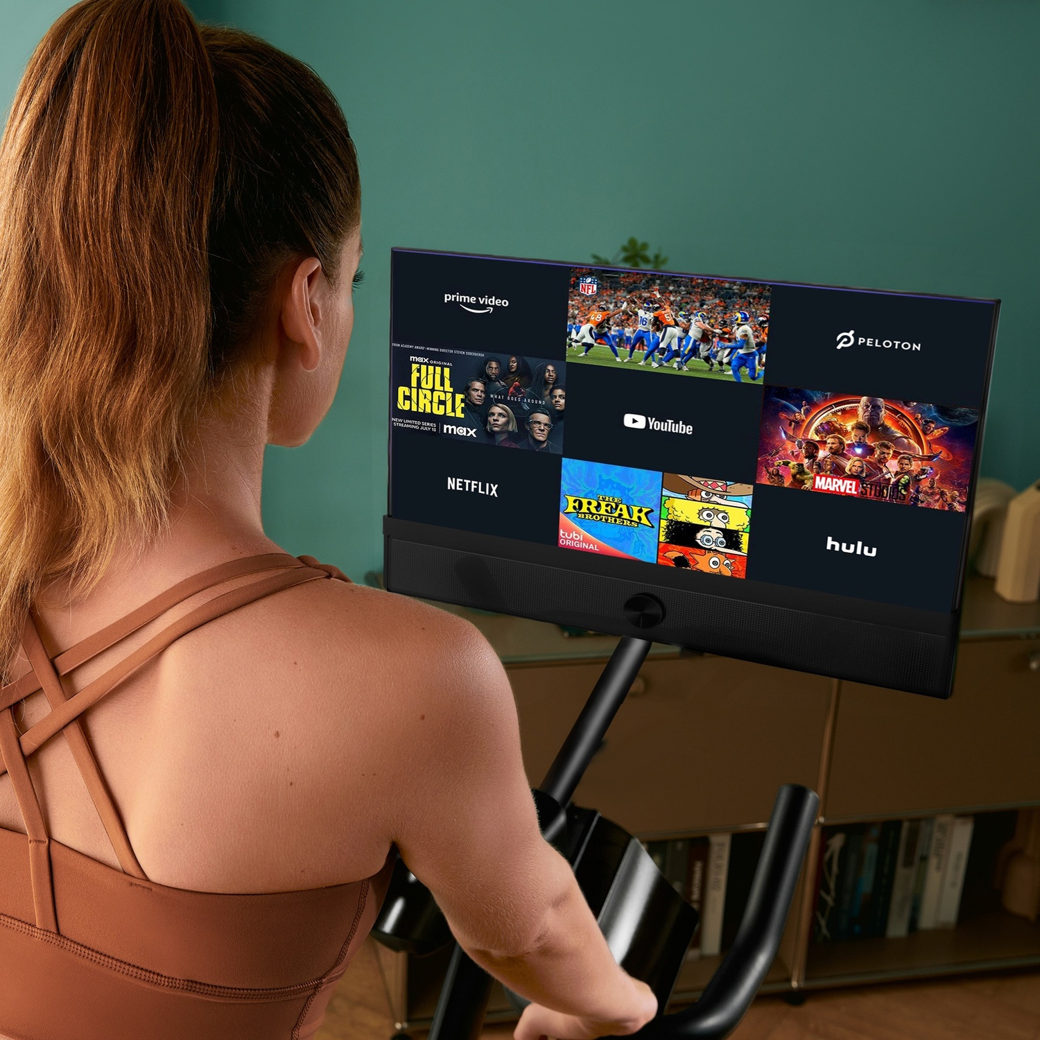 Donna su cyclette guarda schermo con app di streaming.
