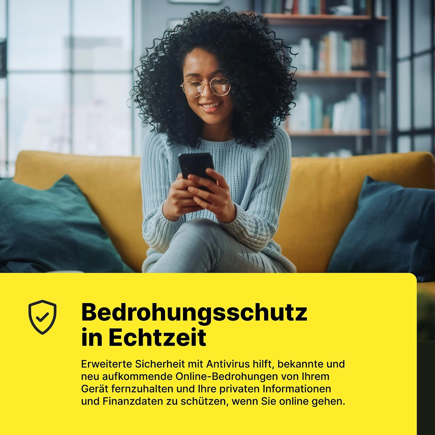 Frau mit lockigen Haaren sitzt auf einem Sofa und schaut auf ihr Handy.