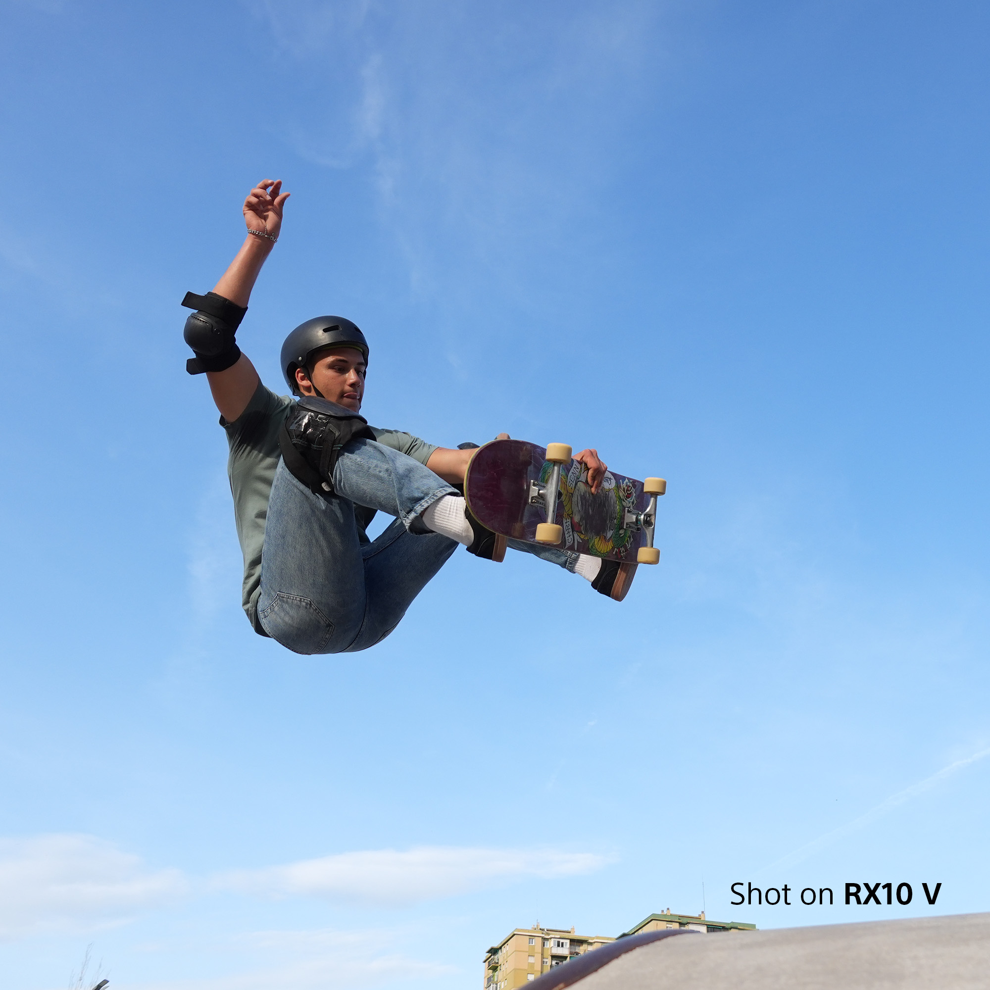 Ein Skateboarder springt in der Luft, mit blauem Himmel und Wolken.