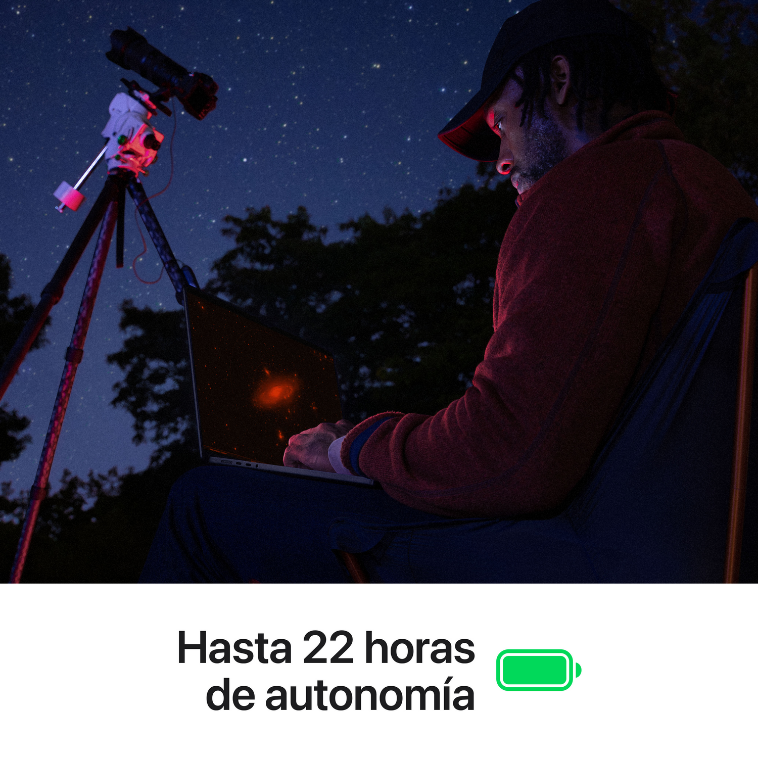 Un hombre mira un portátil bajo un cielo estrellado, con un telescopio al lado.