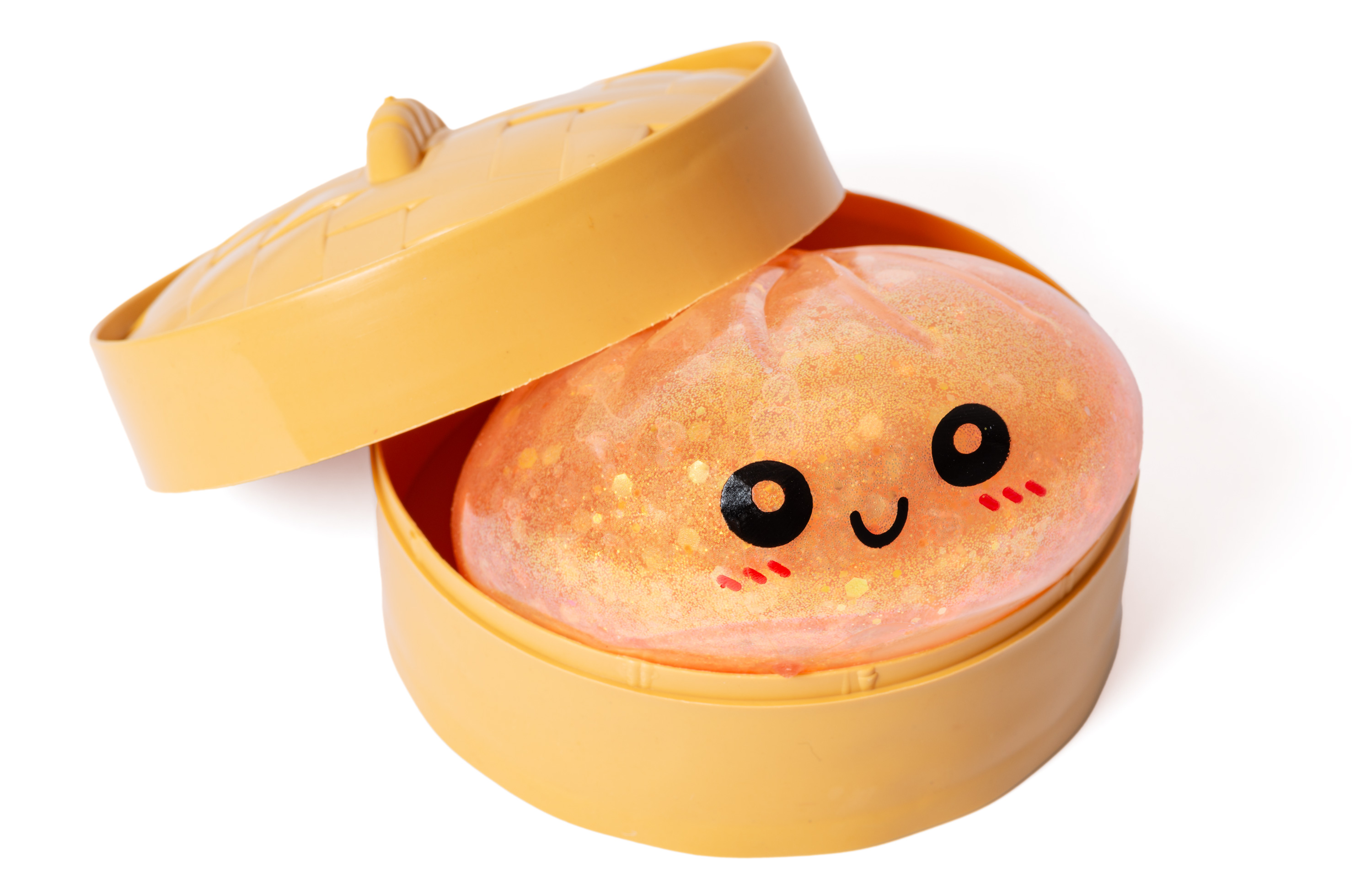 Ein orangefarbener, glitzernder Ball mit Gesicht in einem gelben Behälter.