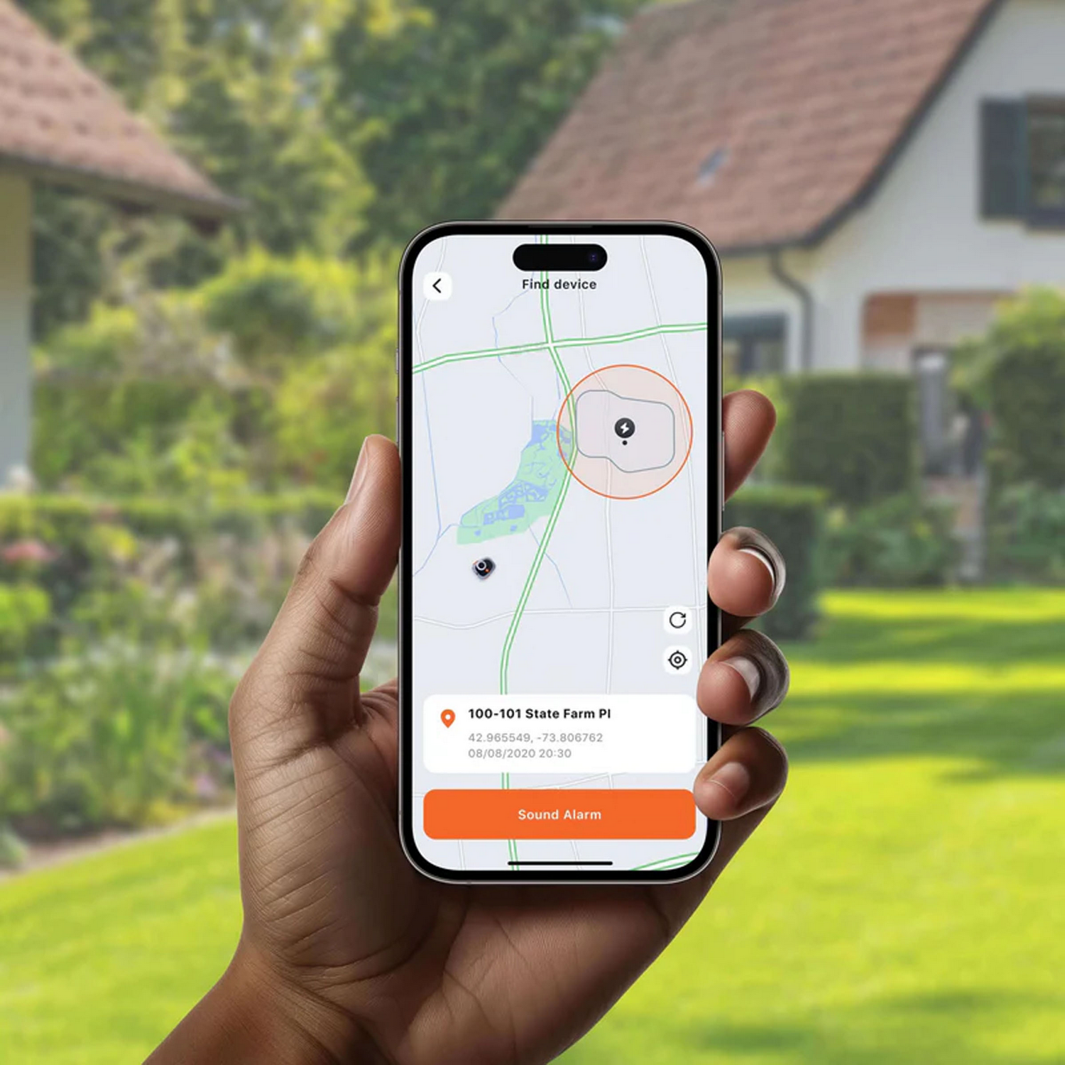 Mano sostiene smartphone con mapa y función de alarma frente a una casa.