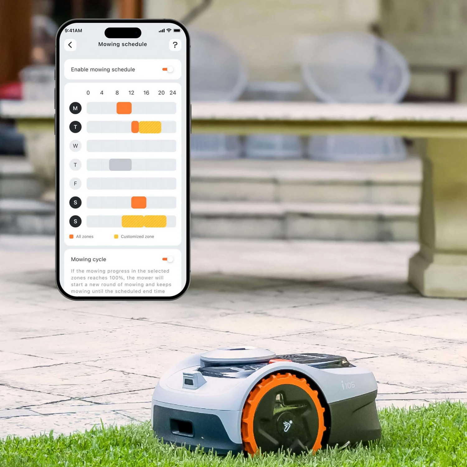 Un robot cortacésped junto a un teléfono que muestra una aplicación de programación de corte.