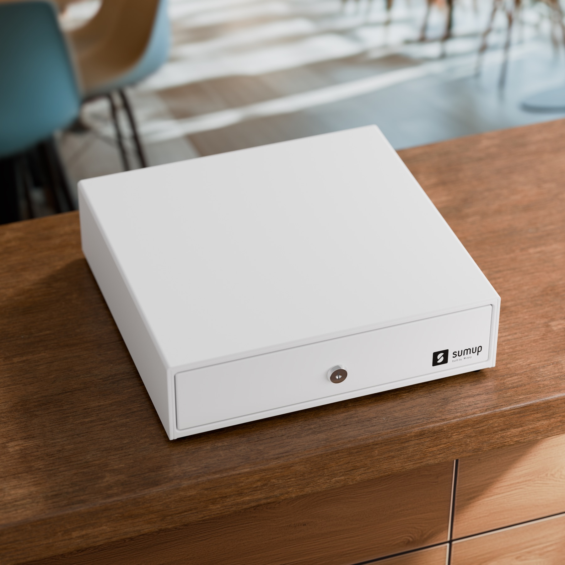 Tiroir-caisse blanc avec serrure sur table en bois.