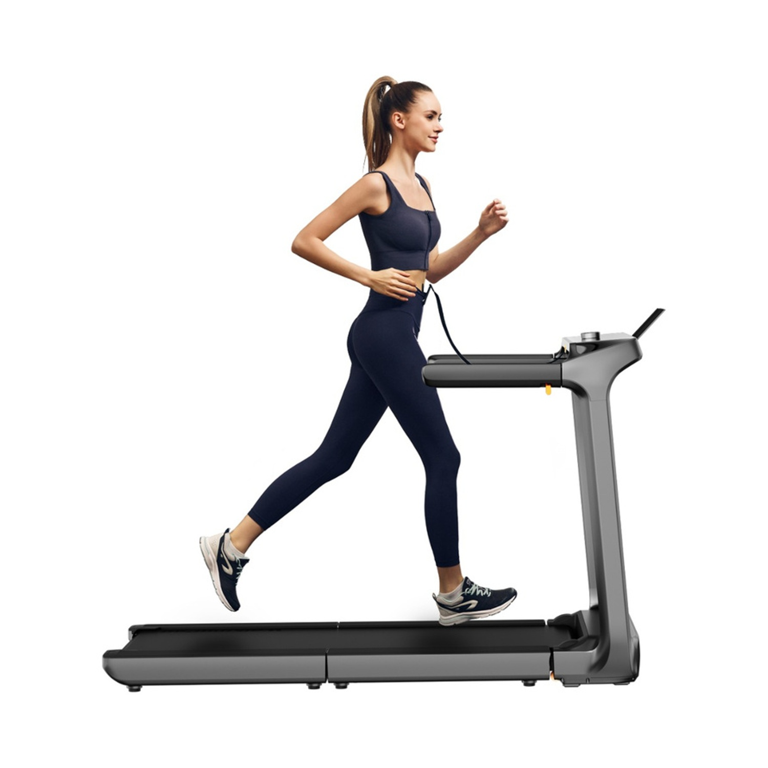 Una donna in abbigliamento sportivo blu navy corre su un tapis roulant grigio.