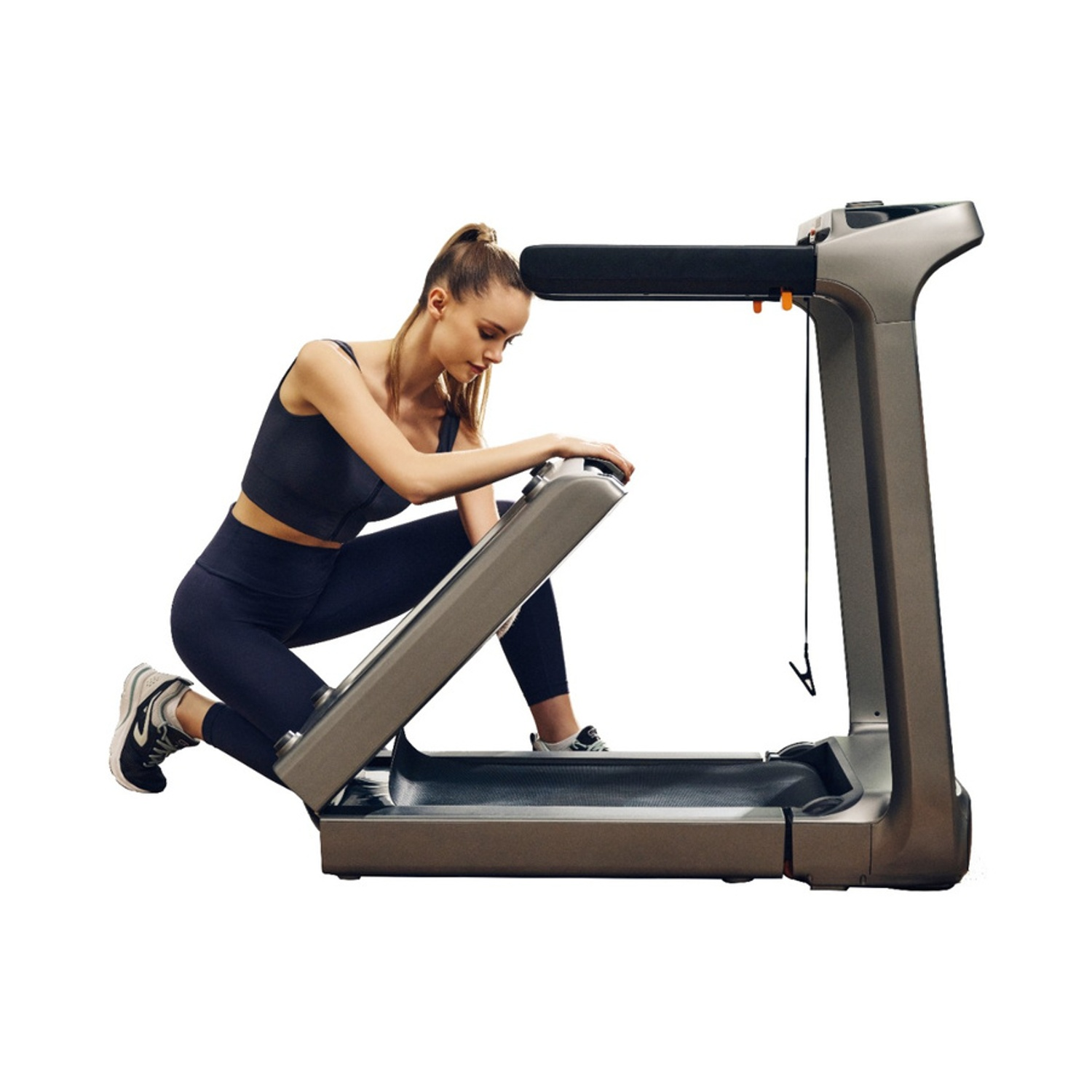 Una donna in abbigliamento sportivo si inginocchia su un tapis roulant. Lo sfondo è bianco.