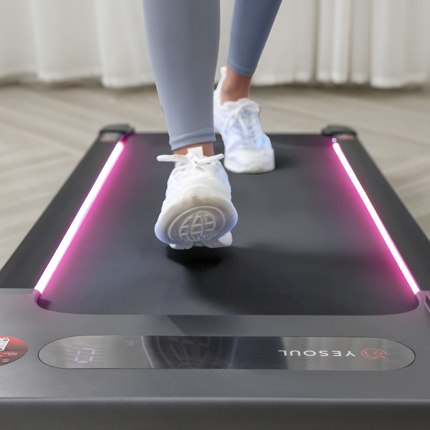 Persona su tapis roulant con luci LED rosa. Primo piano di piedi e scarpe.