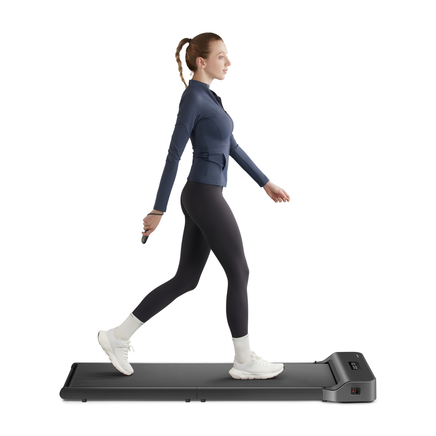 Una donna con la coda di cavallo cammina su un tapis roulant, vestita di blu.