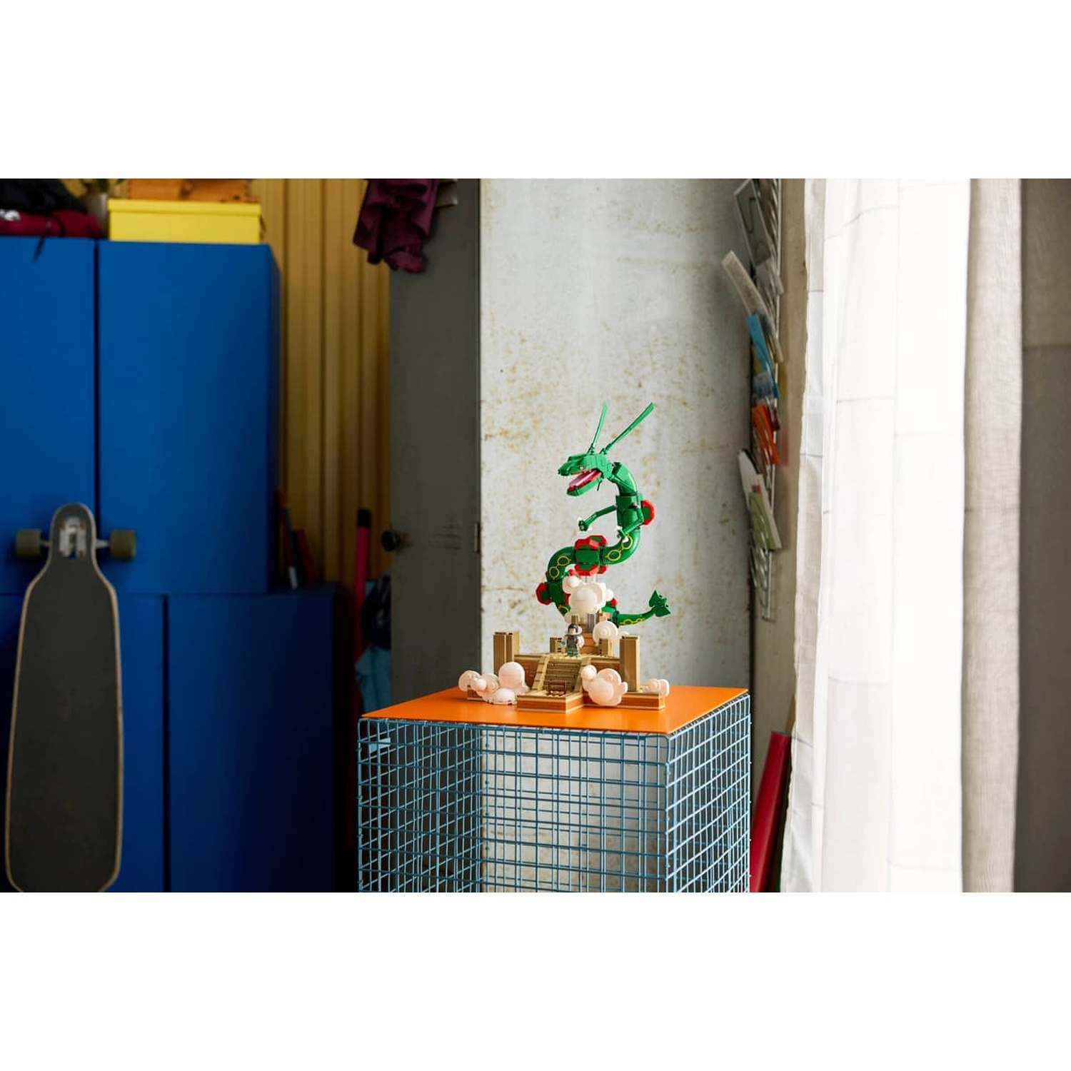 Drago Lego verde su un tavolo arancione accanto a uno skateboard e armadi blu.