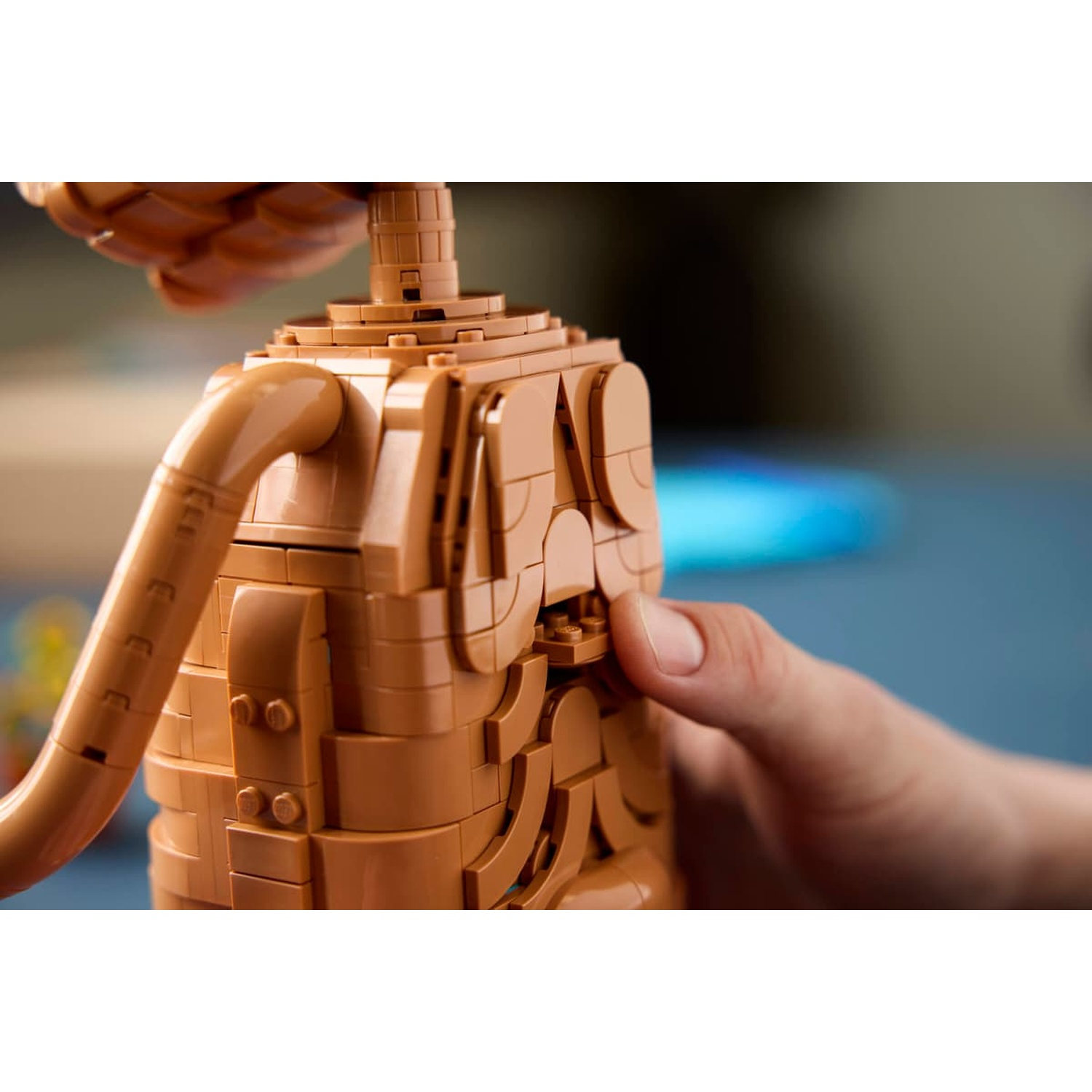 Una mano preme un modello di mattoncino Lego marrone.