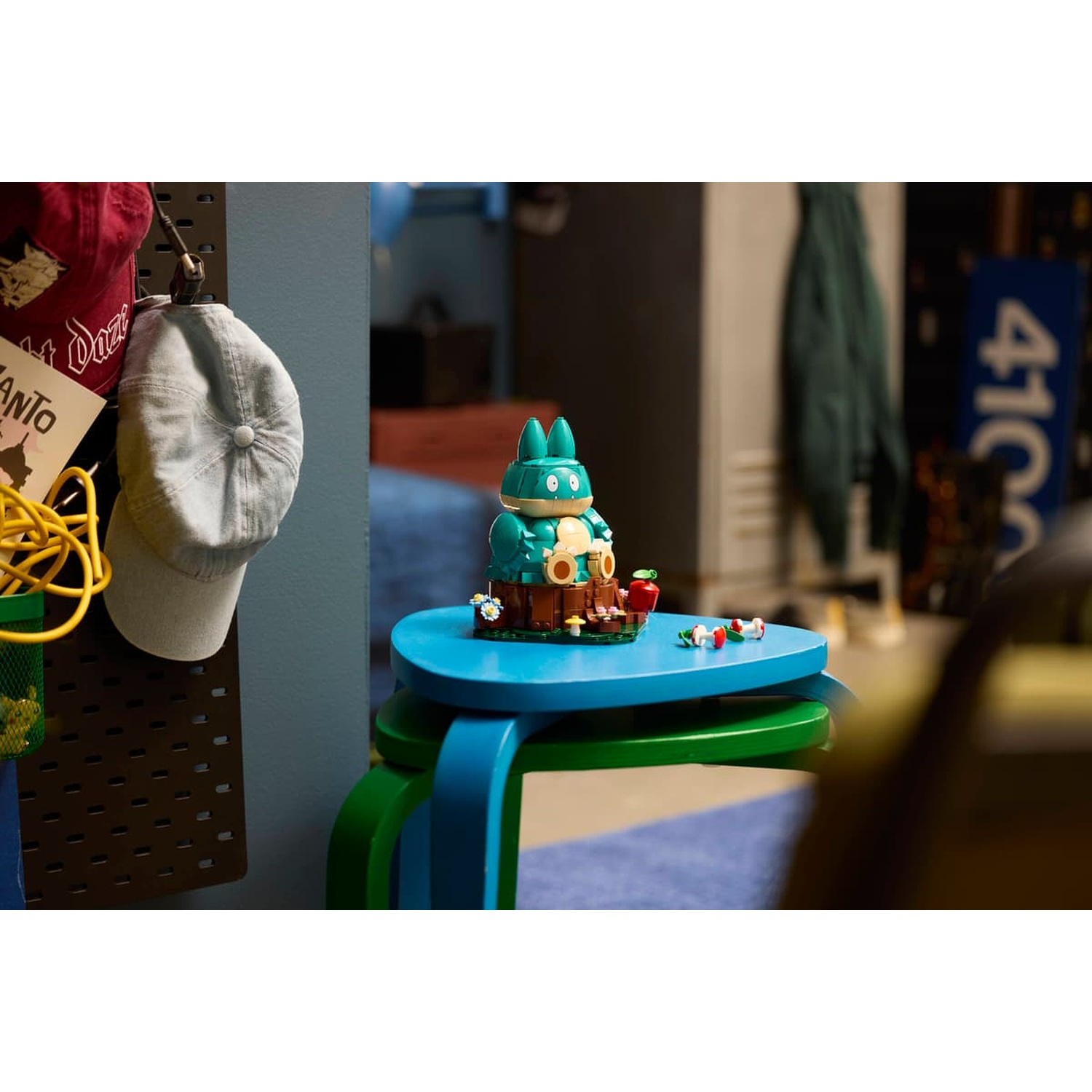 Un personaggio LEGO blu siede su un piedistallo marrone con fiori e funghi.