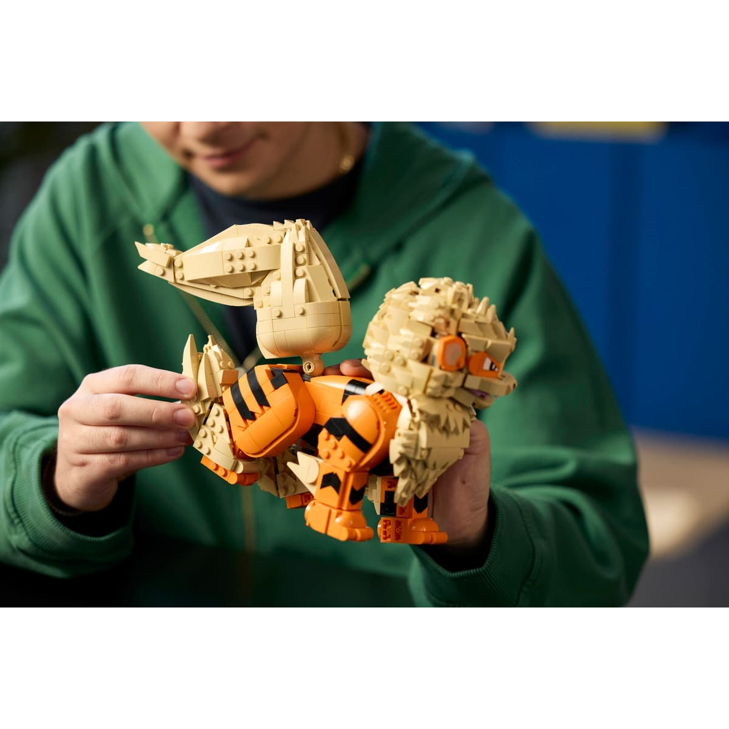 Una persona tiene un modello Lego di cane color cuoio e arancione con strisce nere.