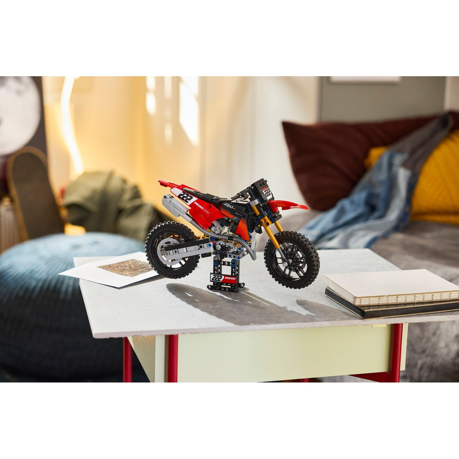 Una moto Lego rossa e nera su un tavolo. Un divano sullo sfondo.