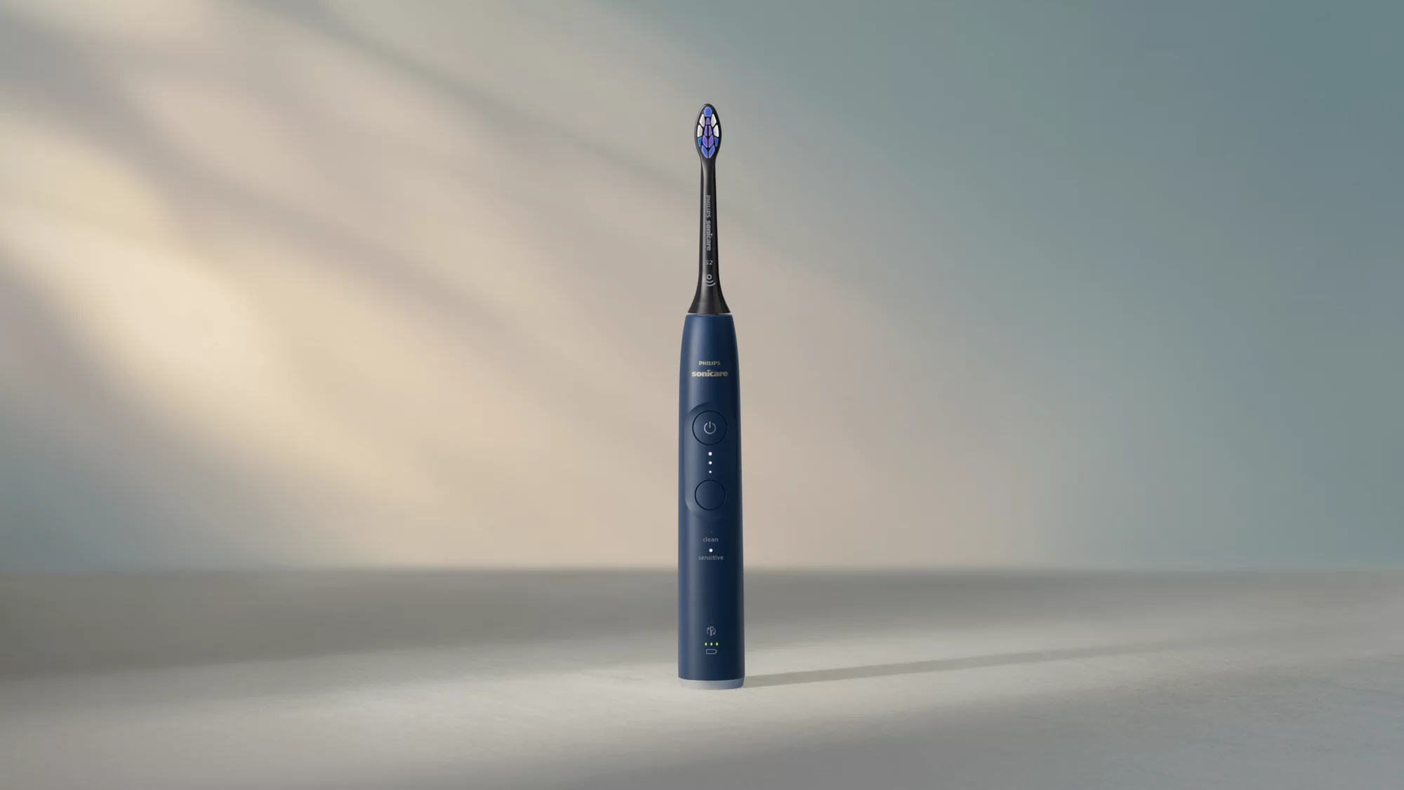 Eine dunkelblaue Philips Sonicare elektrische Zahnbürste steht mittig vor einem grau-blauen Farbverlauf.