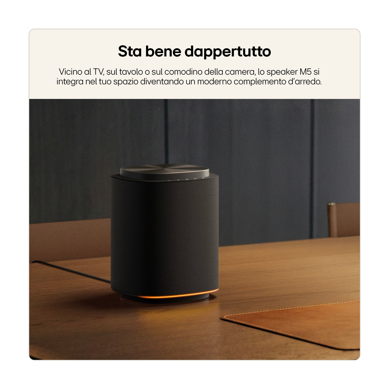 Un altoparlante M5 nero su un tavolo di legno, con illuminazione arancione.