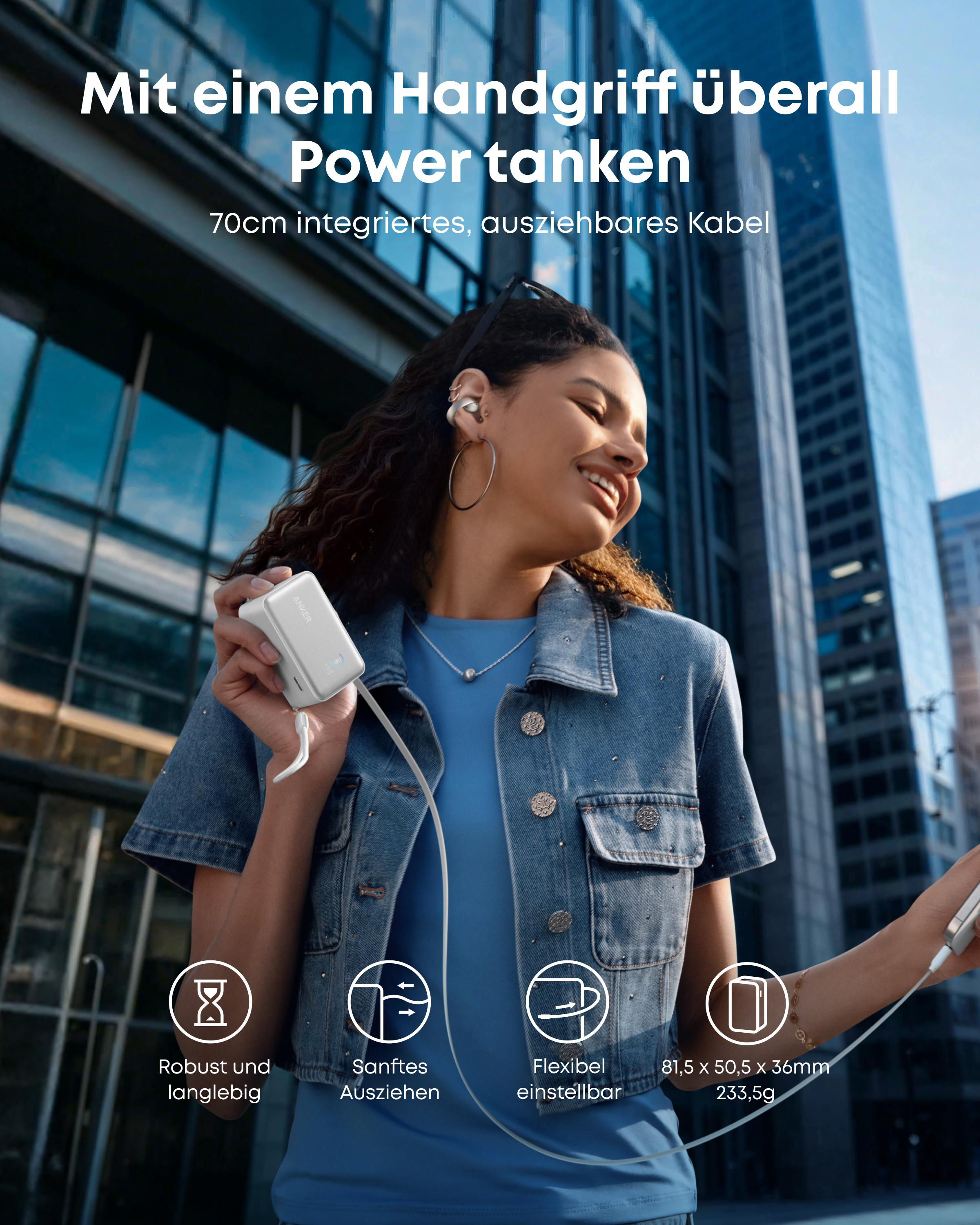 Frau hält eine weiße Powerbank mit ausziehbarem Kabel vor einer modernen Stadtkulisse.