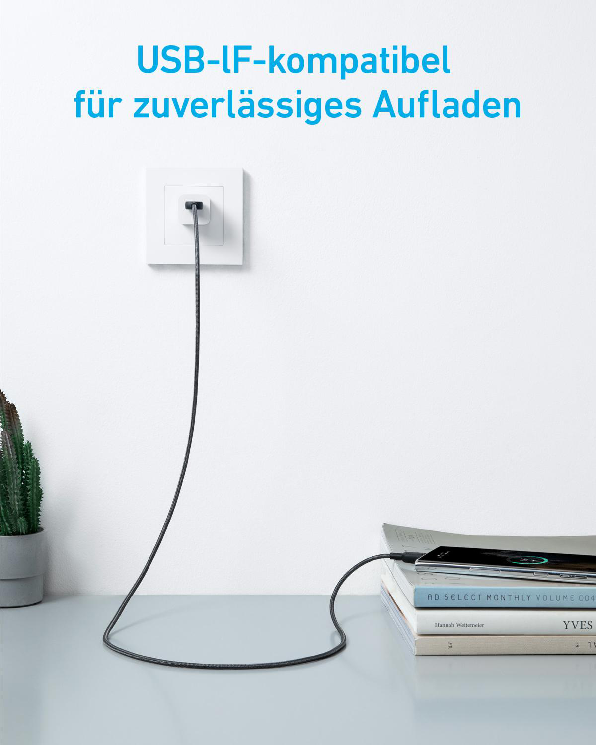 Ein USB-Kabel lädt ein Handy, das auf Büchern liegt.
