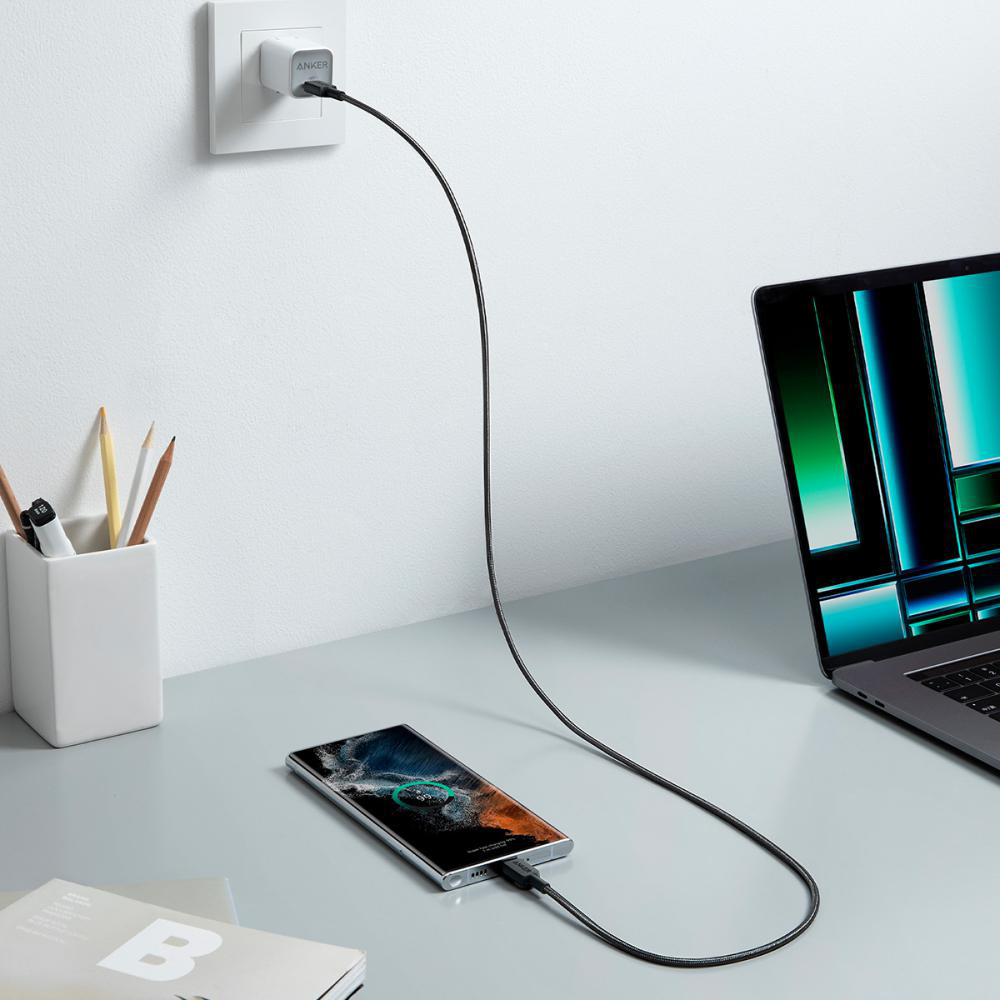 Ein Handy lädt per USB-C von einem Anker-Adapter, der in die Wand eingesteckt ist.