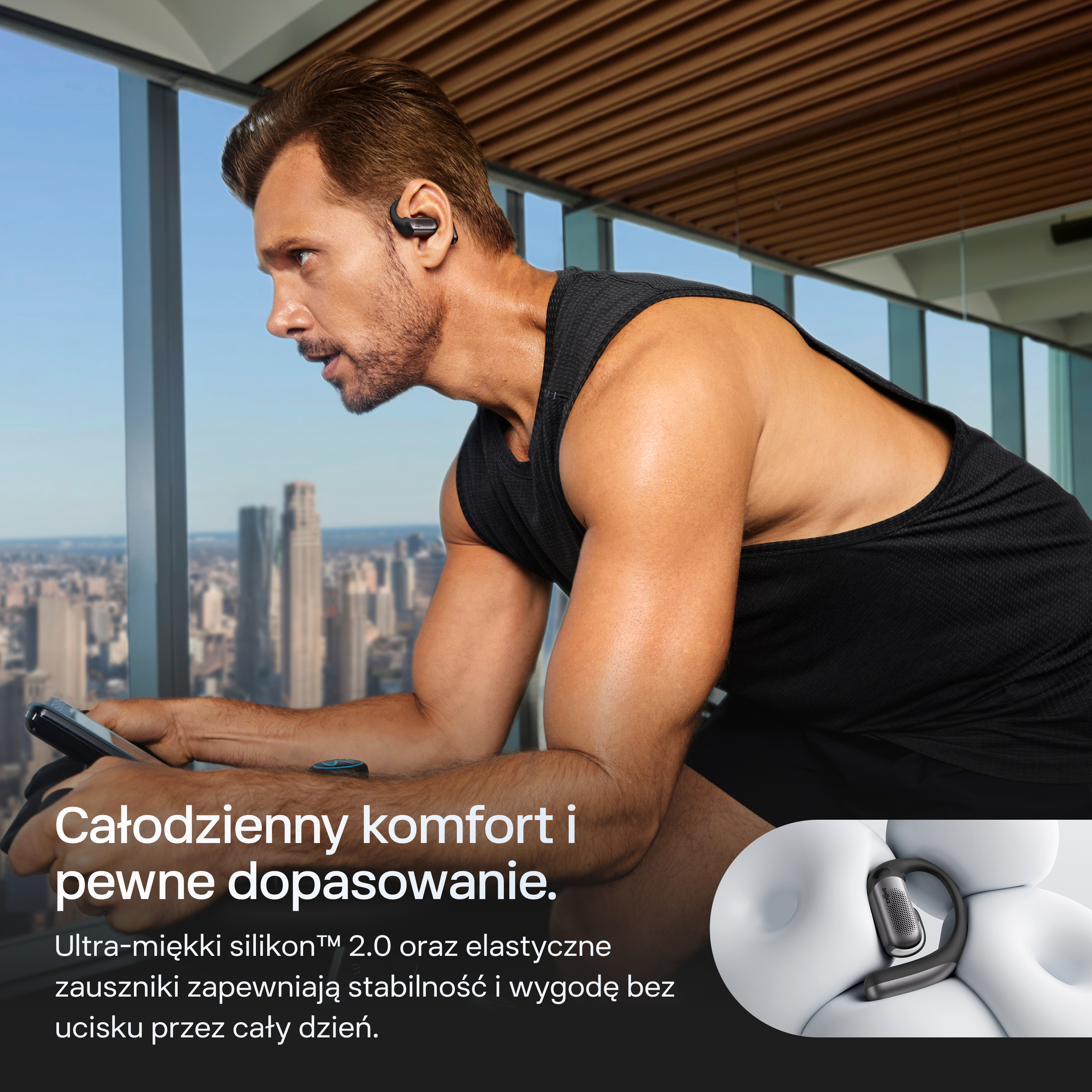 Mężczyzna ćwiczy na rowerze, nosi słuchawki i patrzy na telefon.