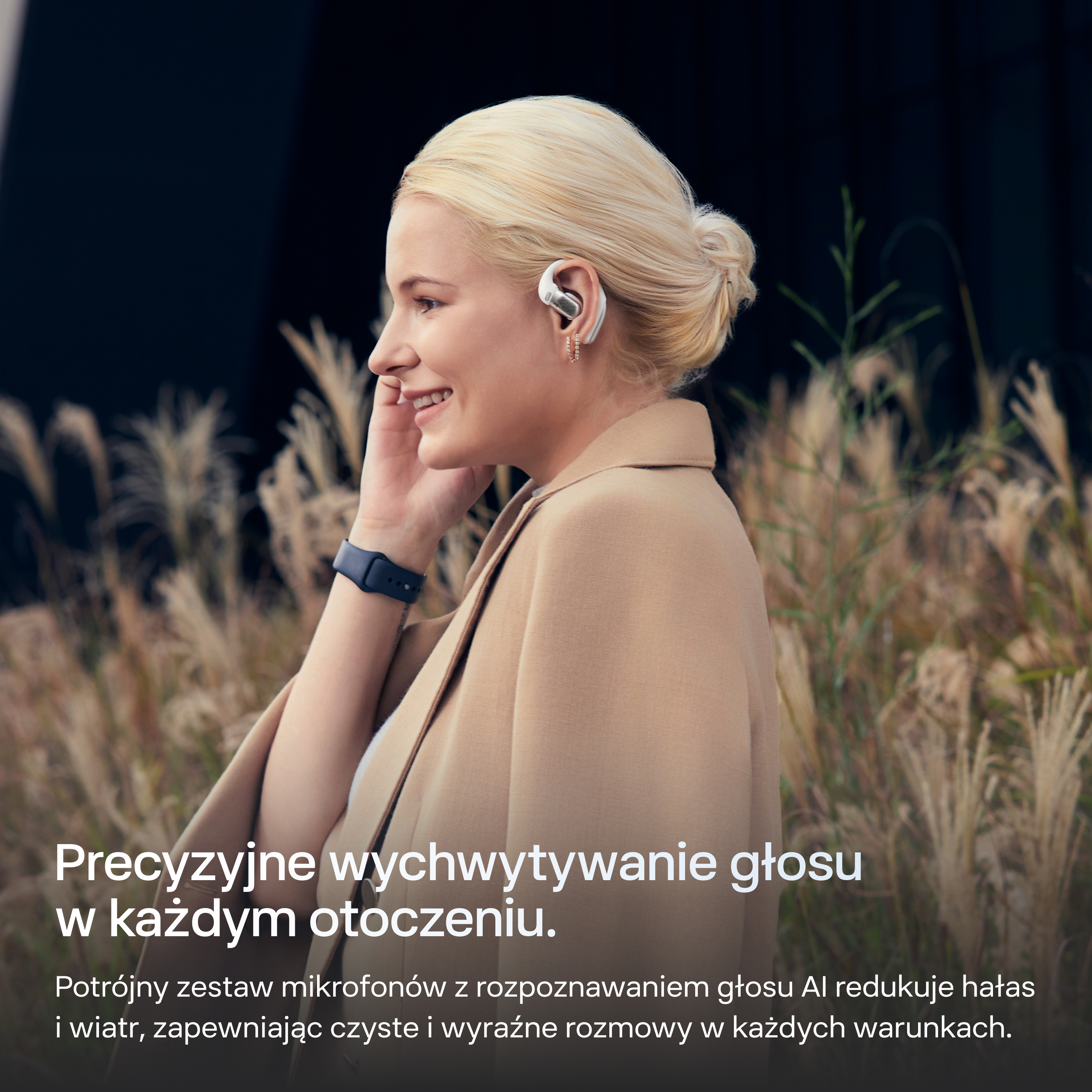 Kobieta z blond włosami nosi białe słuchawki i beżową kurtkę, otoczona roślinami.