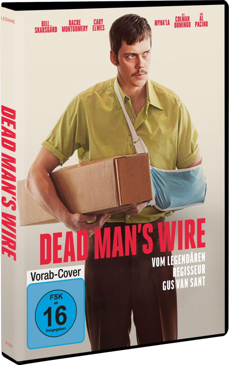 Ein Mann mit gebrochenem Arm trägt einen Karton vor einem Filmplakat.