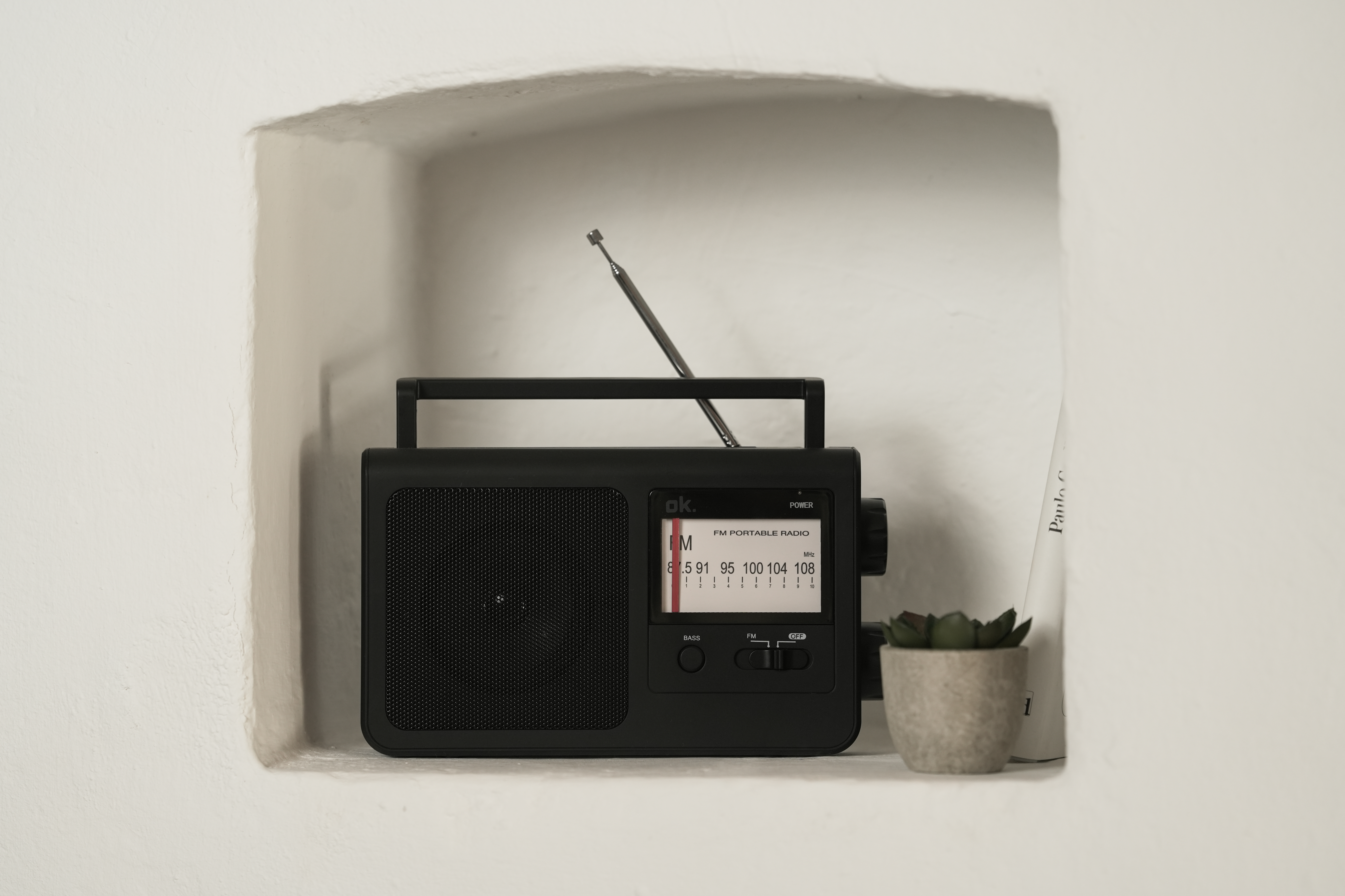 Czarno-białe radio FM z wysuniętą anteną w niszy ściennej.