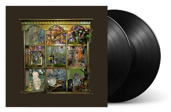 Drei schwarze Vinyl-Schallplatten liegen neben einer kunstvollen, schmalen Schrankfront mit vielen kleinen Szenen.