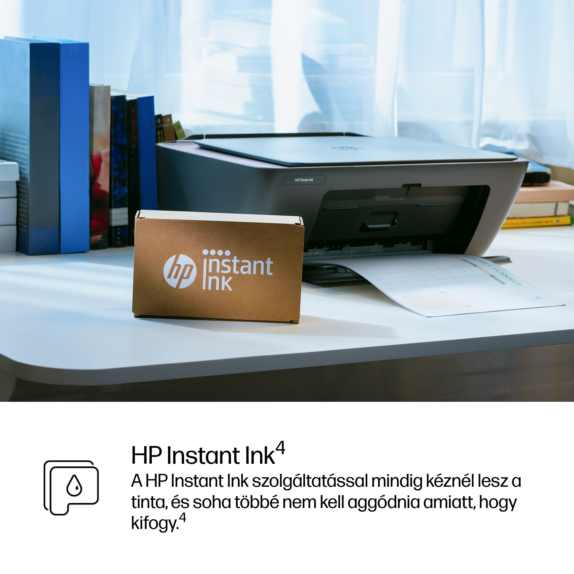 Egy HP nyomtató HP Instant Ink dobozzal és havi tervezővel.