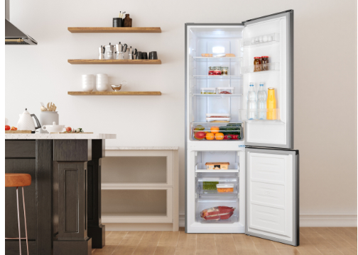 Ein offener Kühlschrank mit Lebensmitteln, daneben eine Küchenzeile mit Obst und Gemüse.