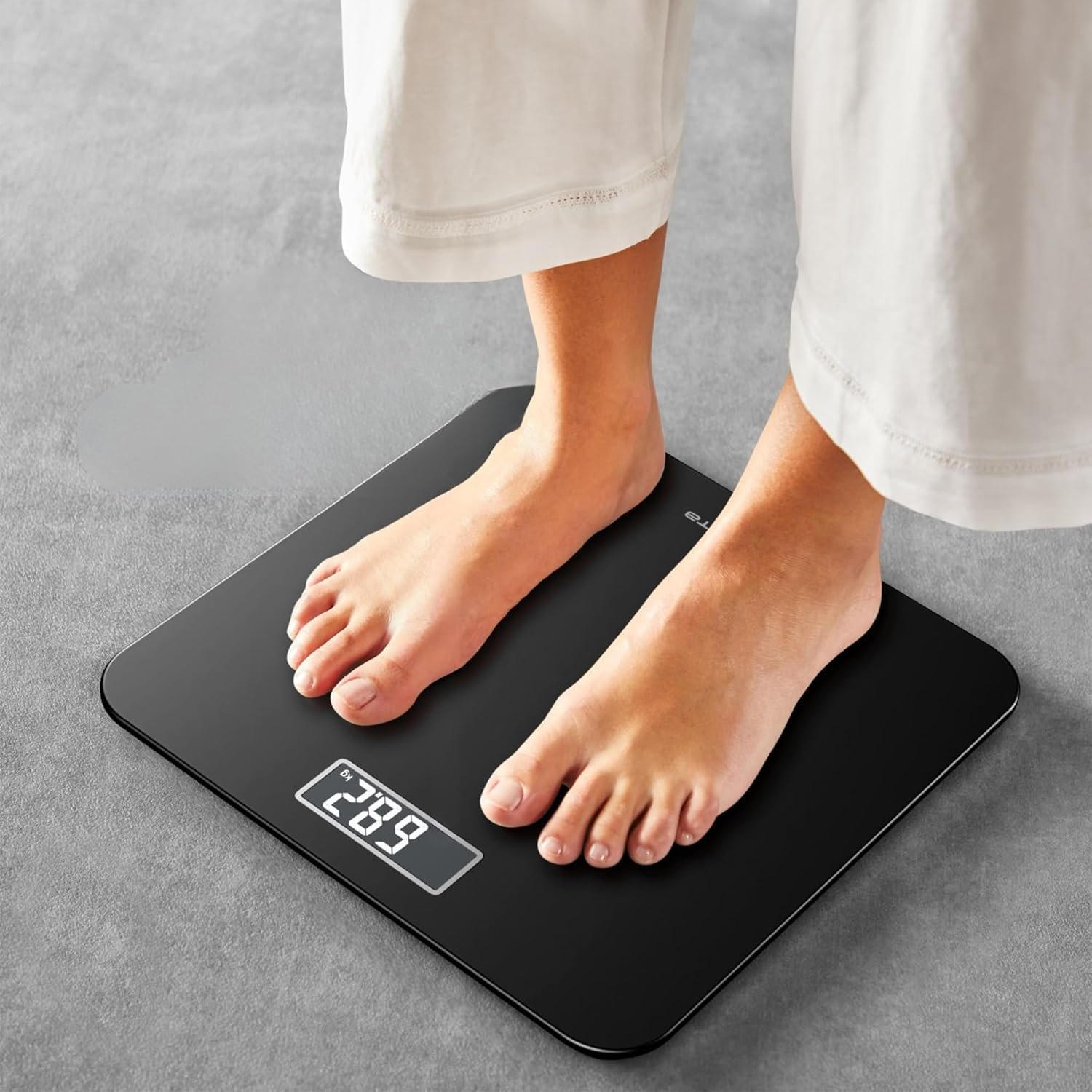 Füße auf einer schwarzen Digitalwaage, die 28,9 kg anzeigt.