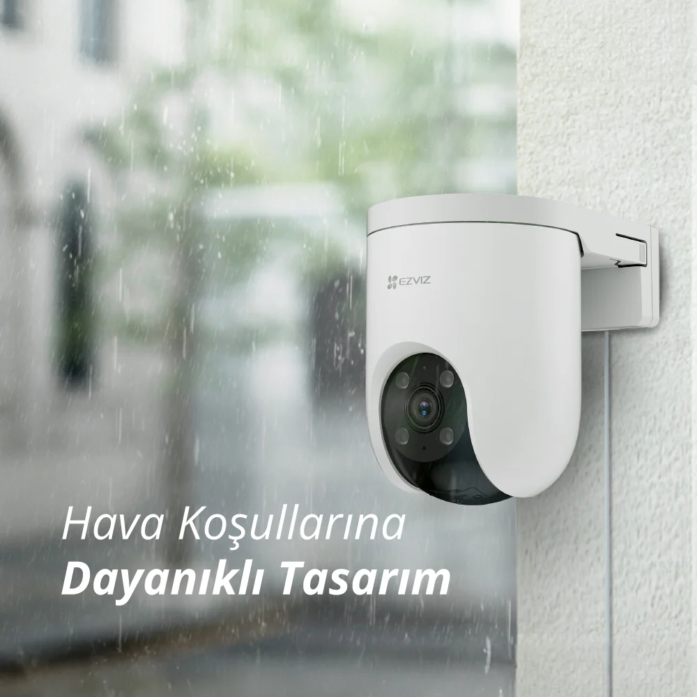 Yağmurda duvara monte edilmiş beyaz güvenlik kamerası.