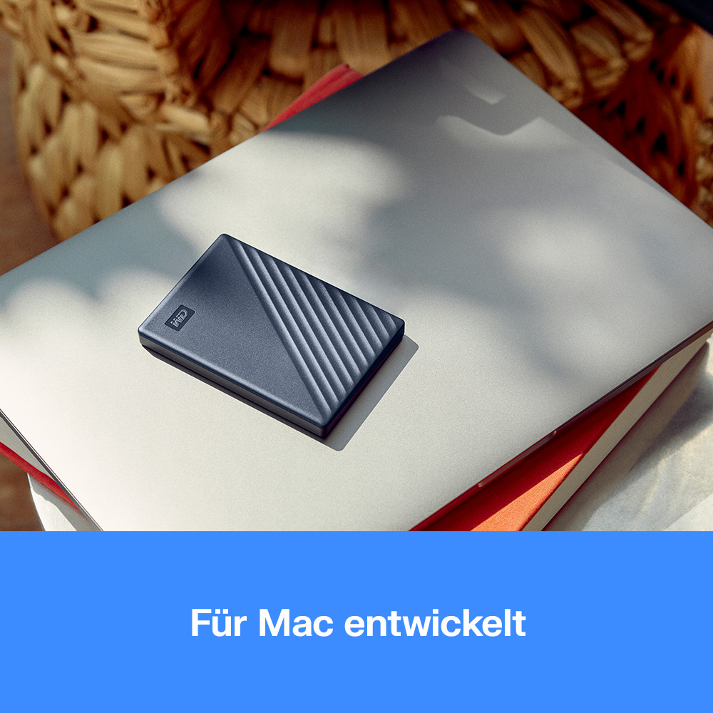 Eine dunkle Festplatte liegt auf einem geöffneten Laptop. Im Hintergrund ein Korb.
