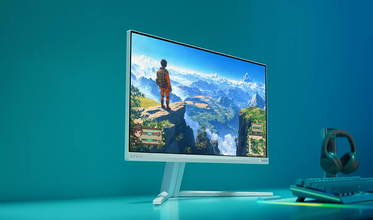 Ein Monitor zeigt ein Spiel mit einer Figur auf einem Berggipfel. Kopfhörer und Tastatur daneben.