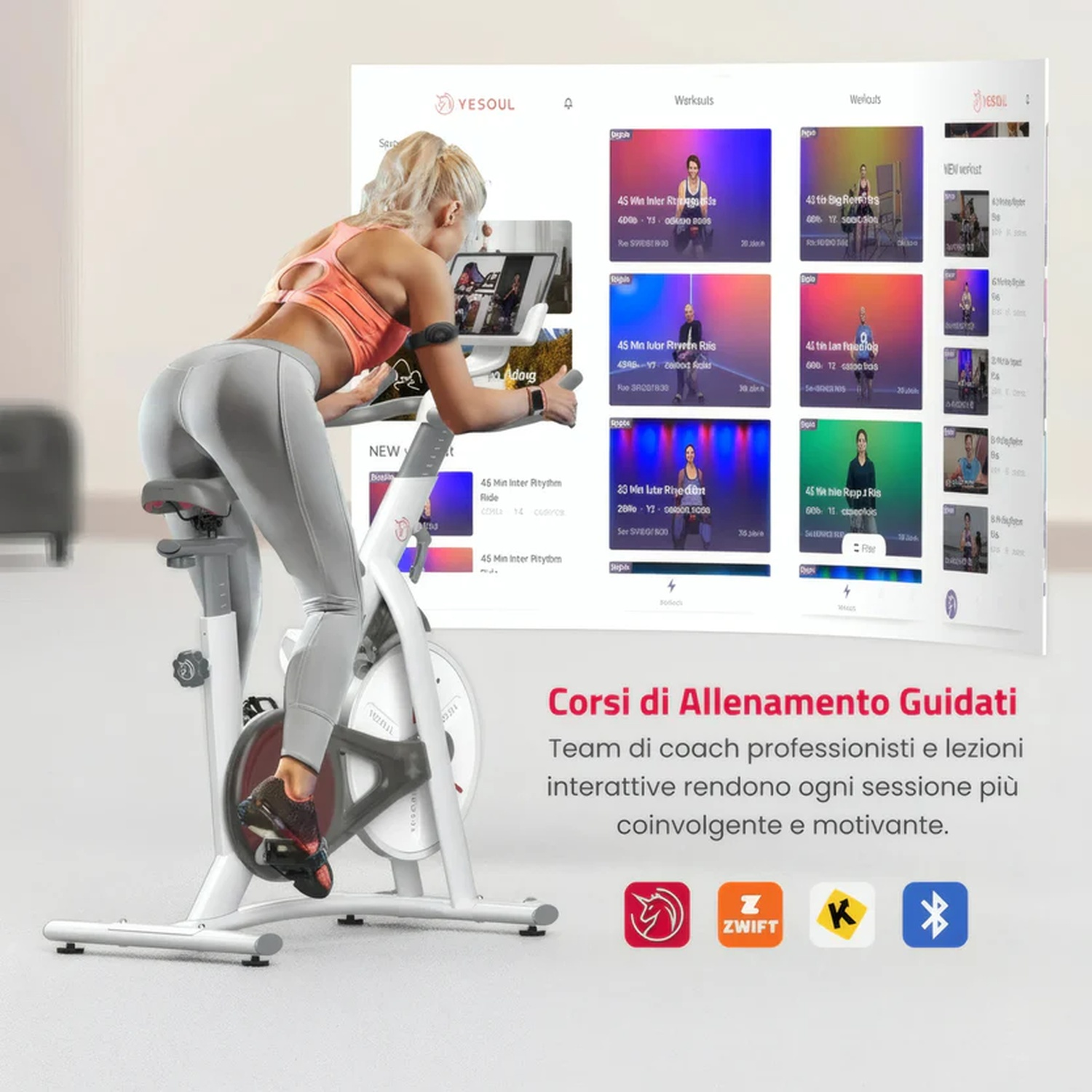 Una donna pedala su una cyclette bianca davanti a uno schermo con corsi di allenamento.