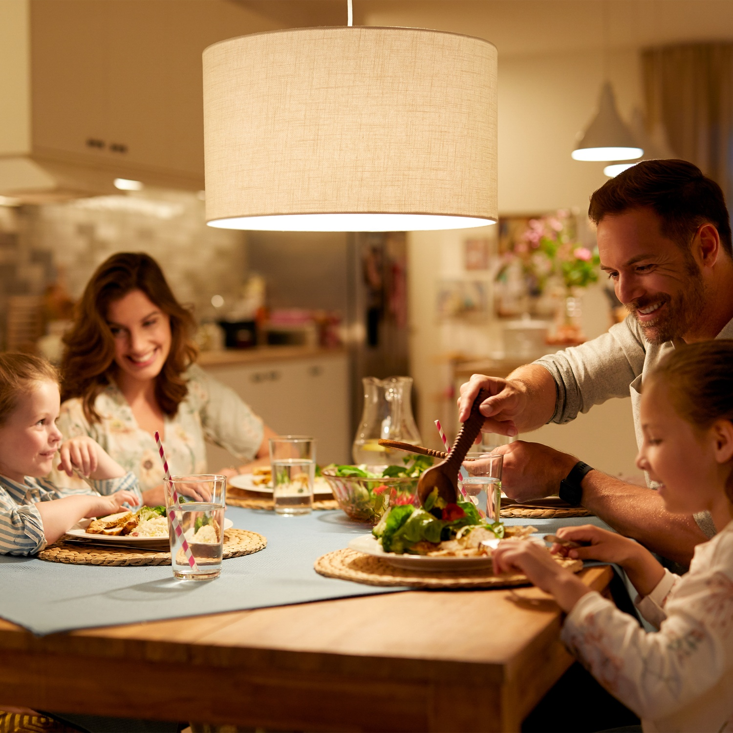 Une famille dîne à table. Le père sert de la salade.