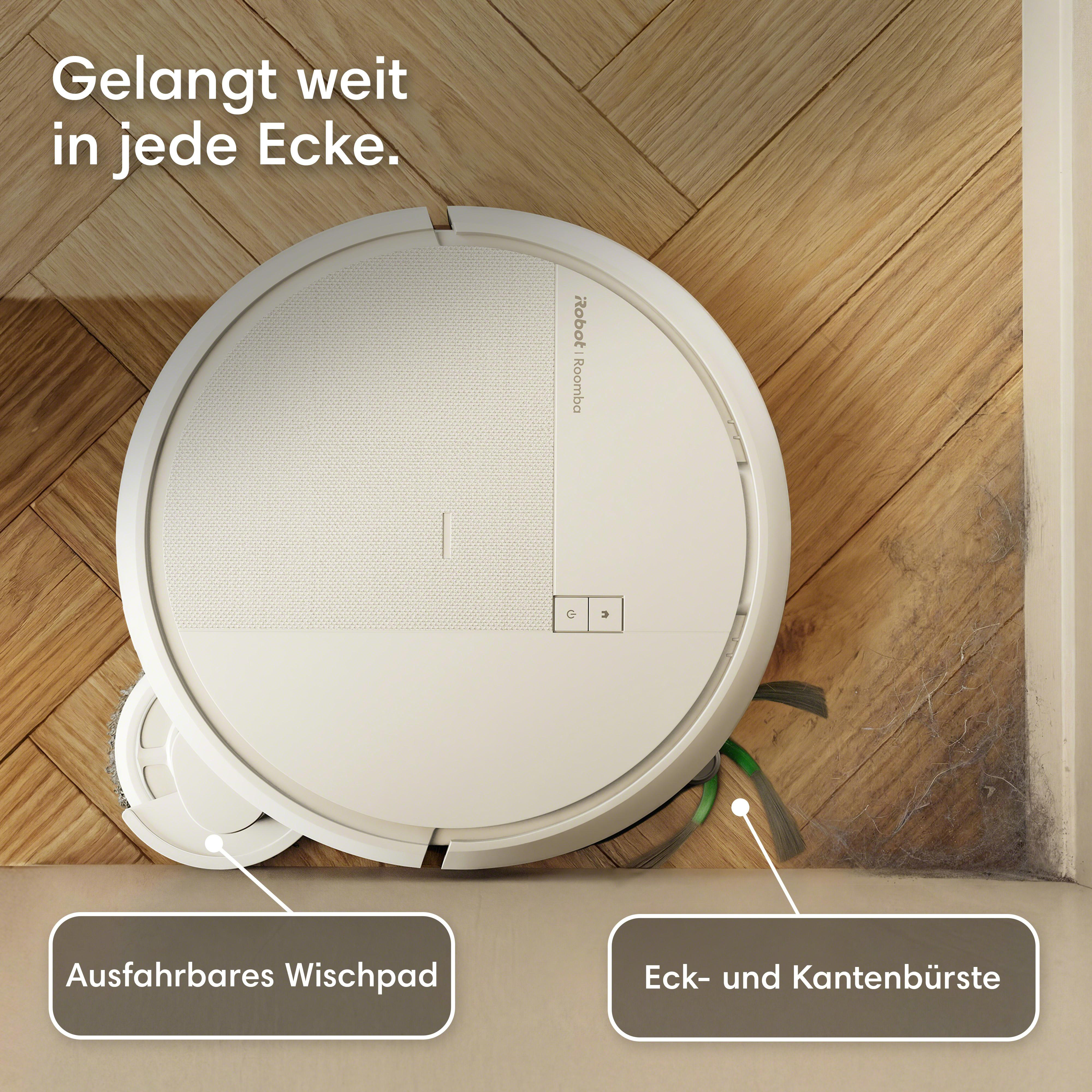 Ein weißer Saugroboter reinigt auf einem Holzboden nahe einer Ecke mit Staub.