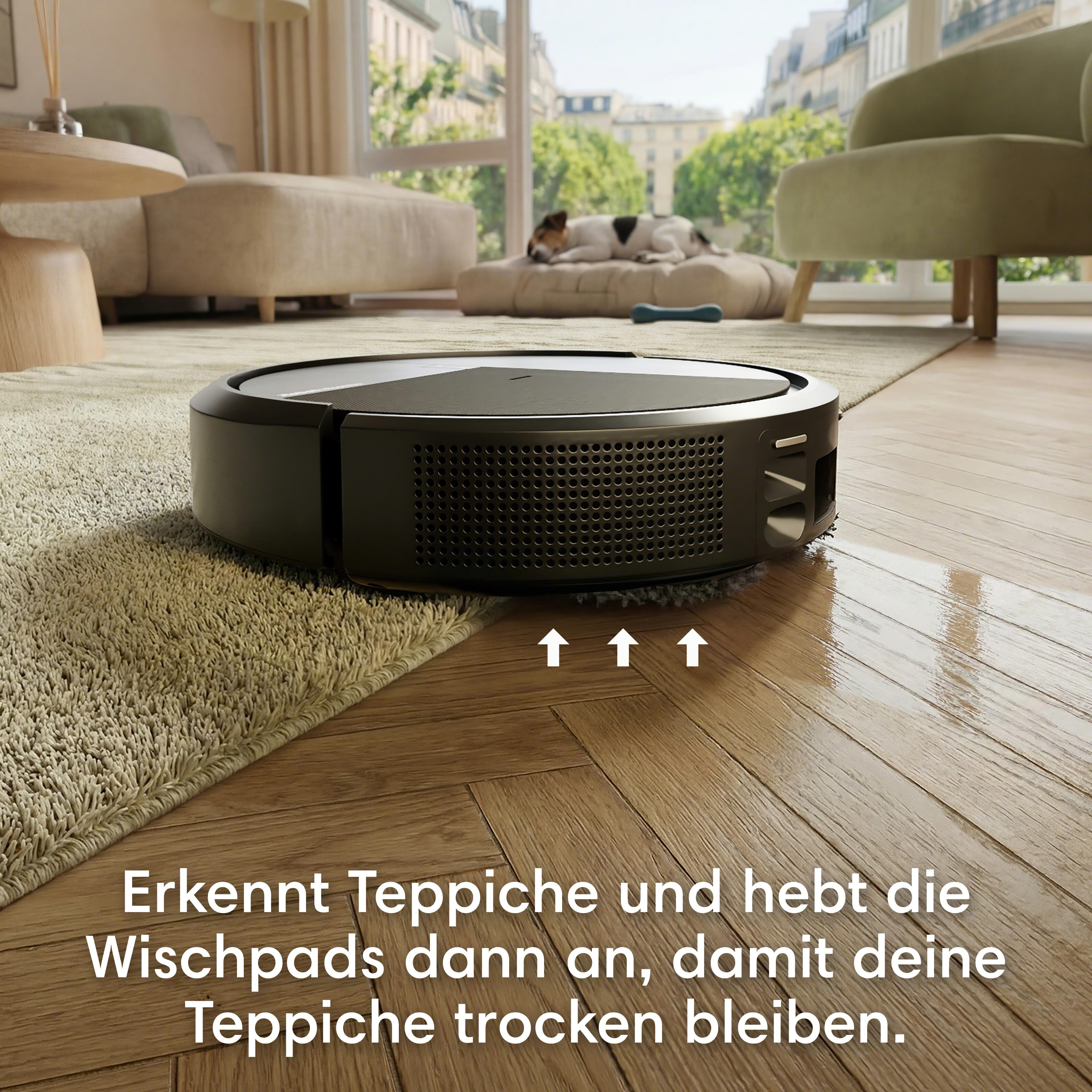 Ein Saugroboter reinigt einen Holzboden und eine Teppichkante.