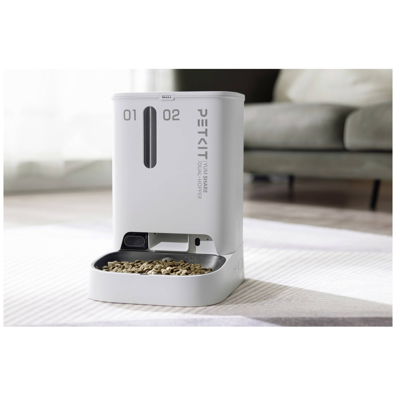 A white dual-hopper automatic pet feeder with a food bowl filled with kibble.