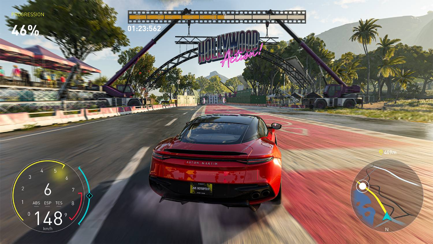 Un Aston Martin rojo conduce en una pista de carreras bajo el arco Hollywood Action.