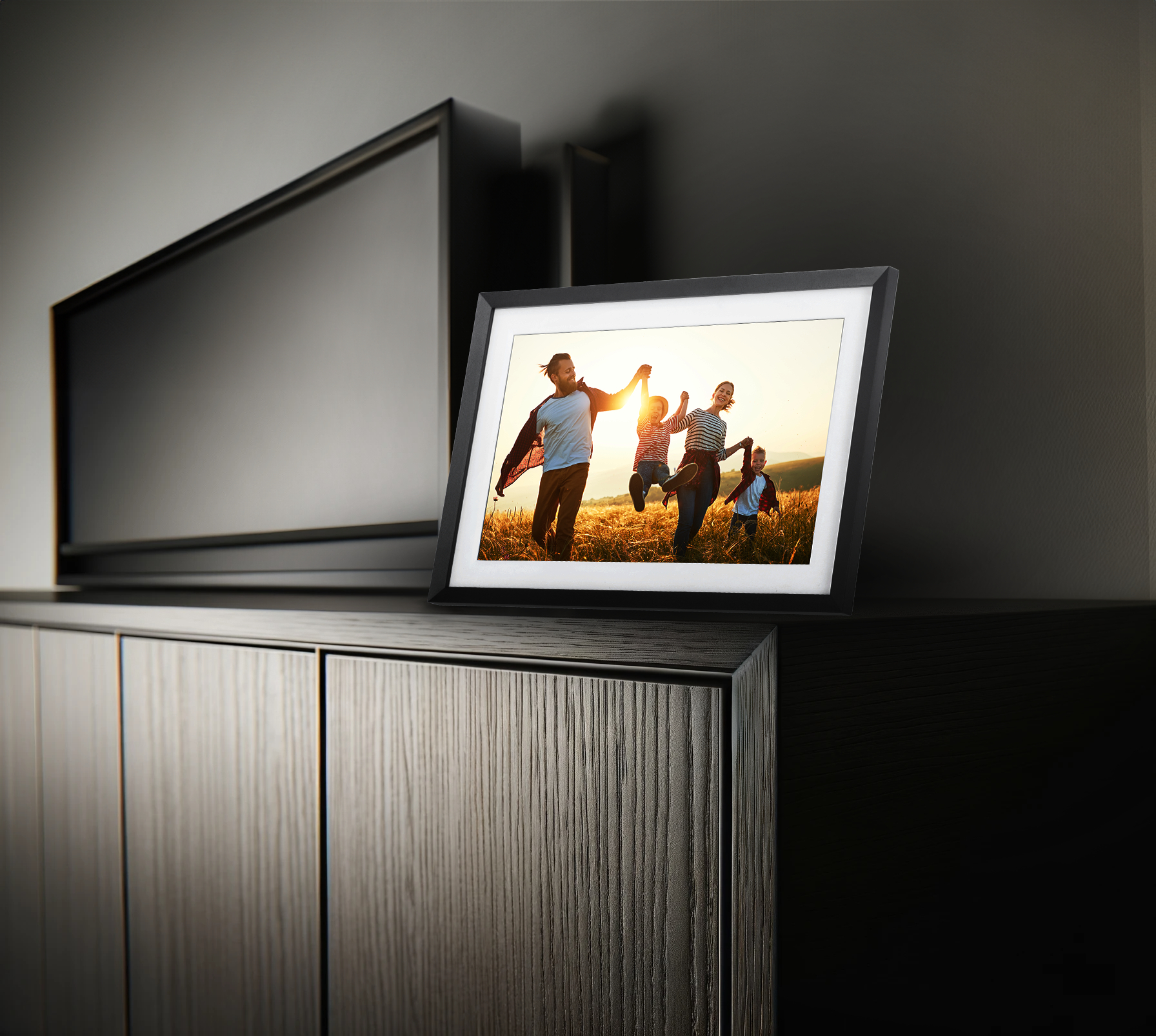 Gerahmtes Foto einer Familie, die auf einem sonnenbeschienenen Weizenfeld auf einer Kommode rennt.
