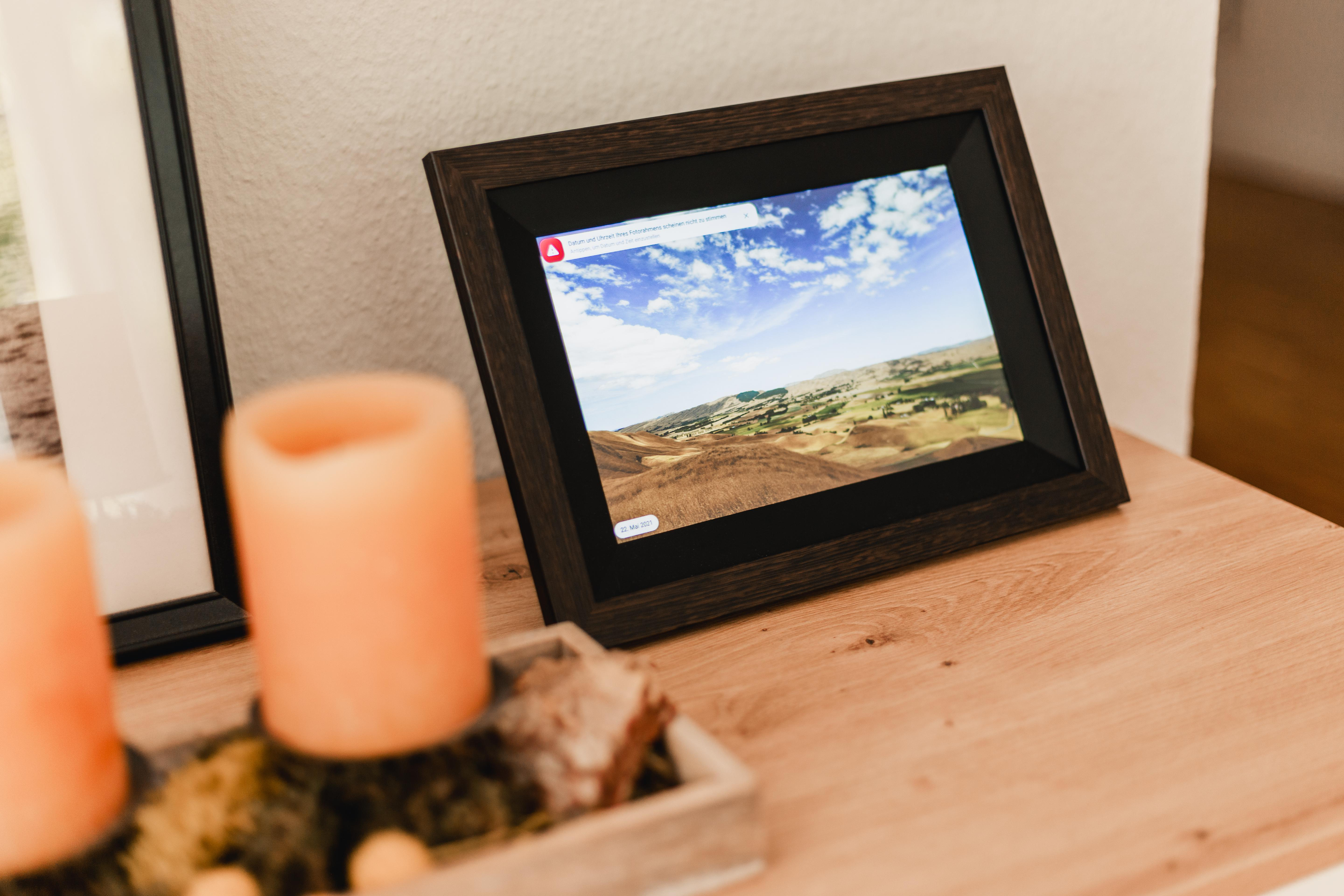 Ein digitaler Bilderrahmen zeigt eine Landschaft mit blauen Himmel und Wolken.