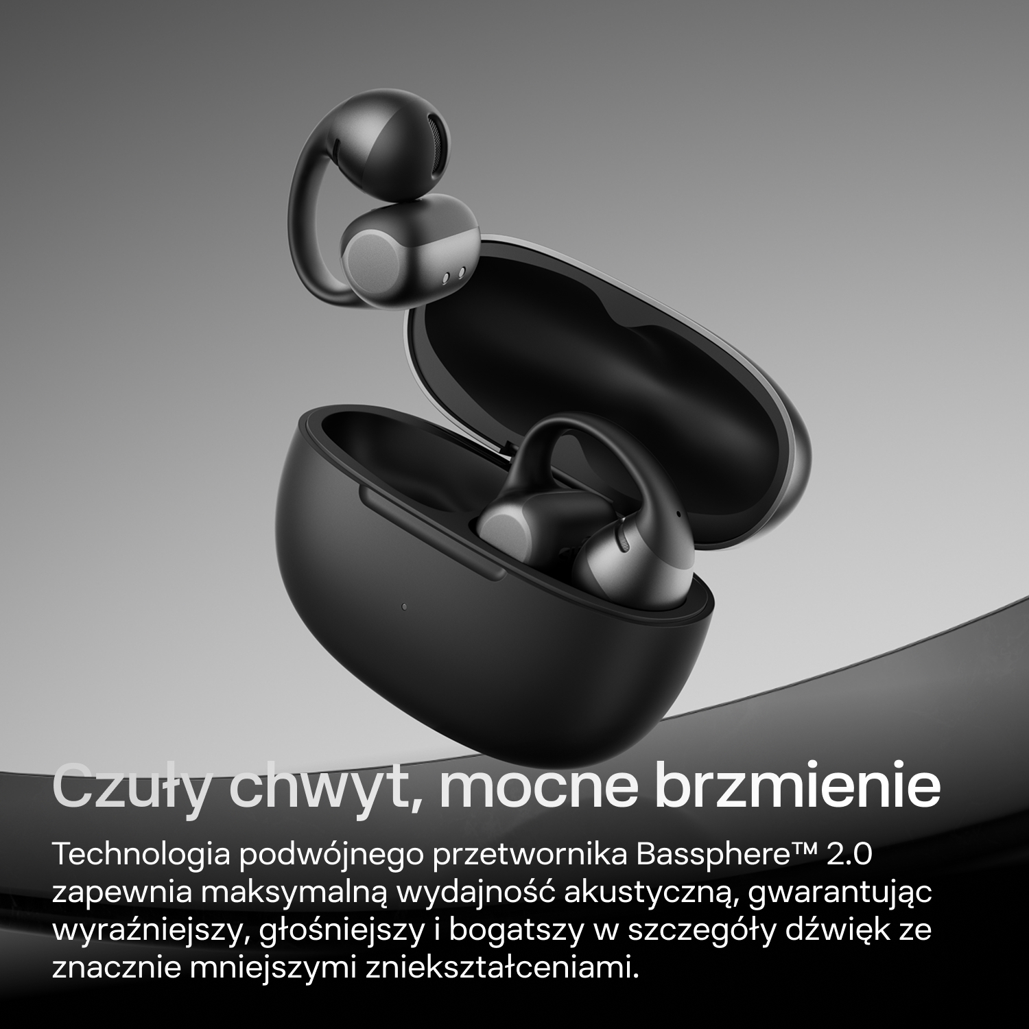 Czarne słuchawki bezprzewodowe z etui ładującym na szarym tle.
