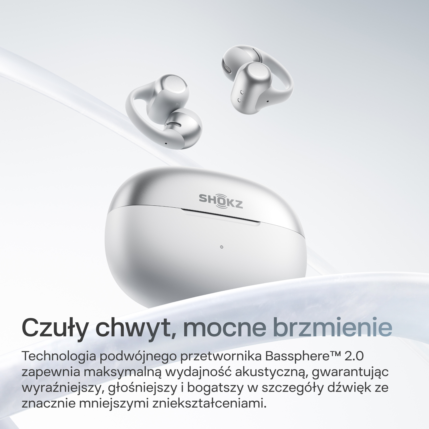 Srebrne słuchawki Shokz i etui ładujące na jasnym tle.