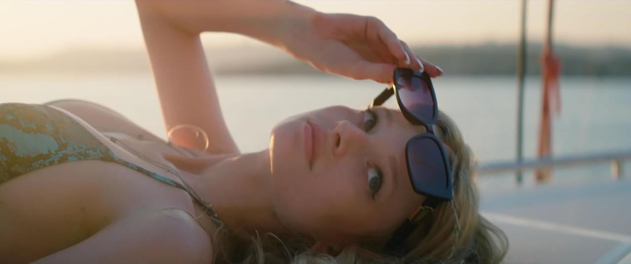 Eine Frau mit Sonnenbrille auf einem Boot, die in die Kamera blickt.
