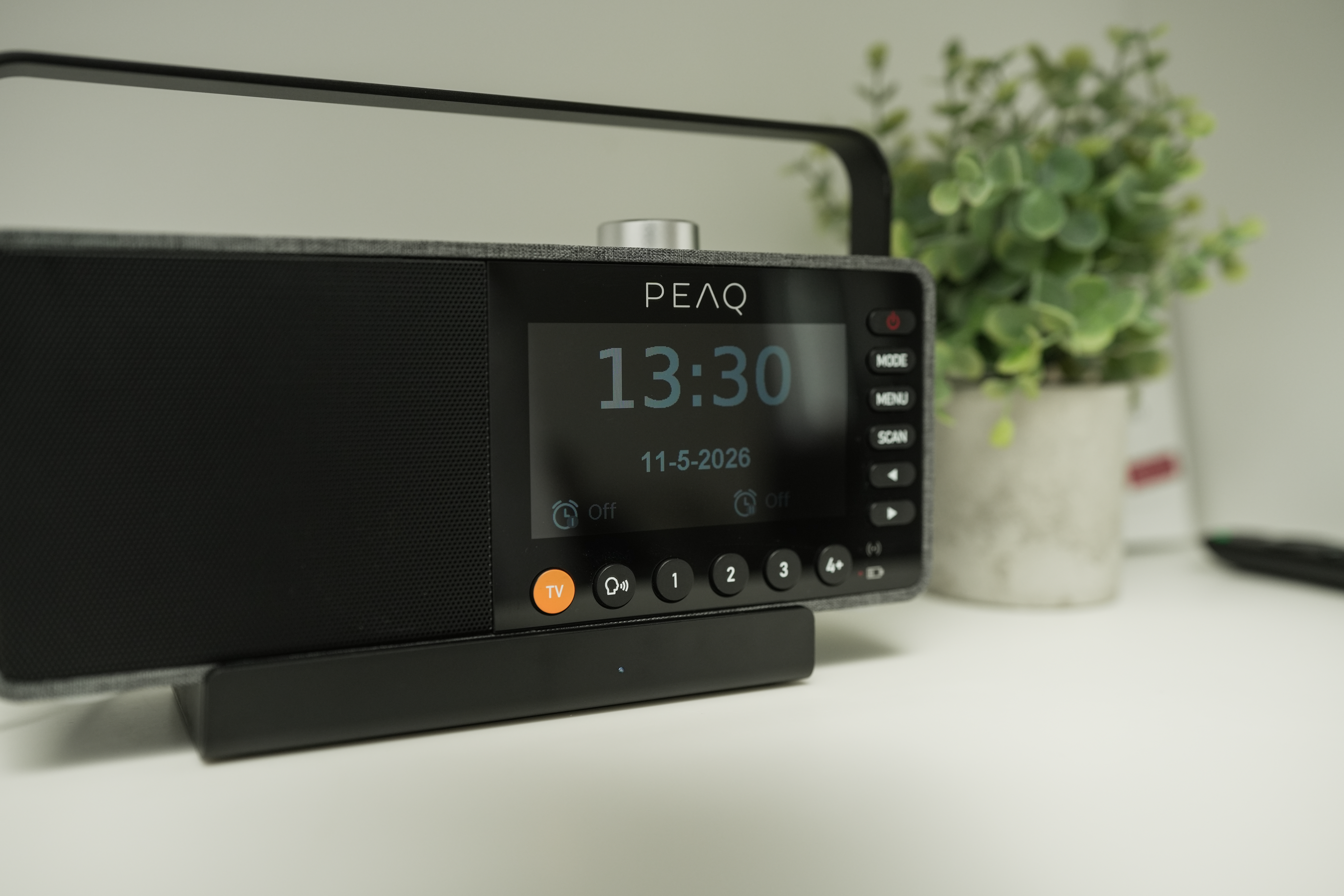 Ein schwarzer PEAQ Radiowecker mit einem digitalen Display, das 13:30 Uhr anzeigt.