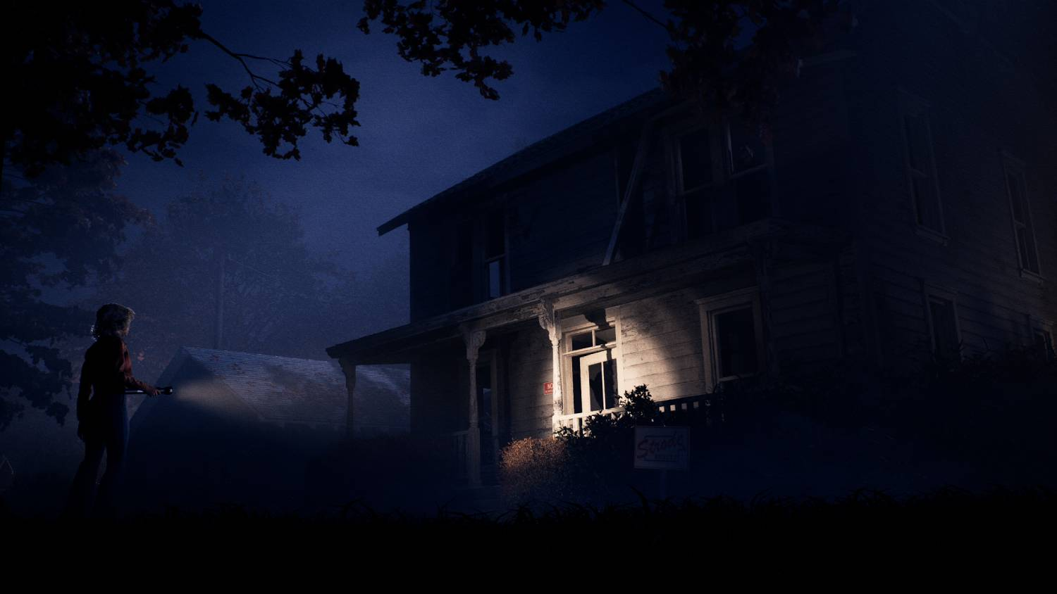 Una persona con una linterna está afuera de una casa oscura y vieja por la noche.